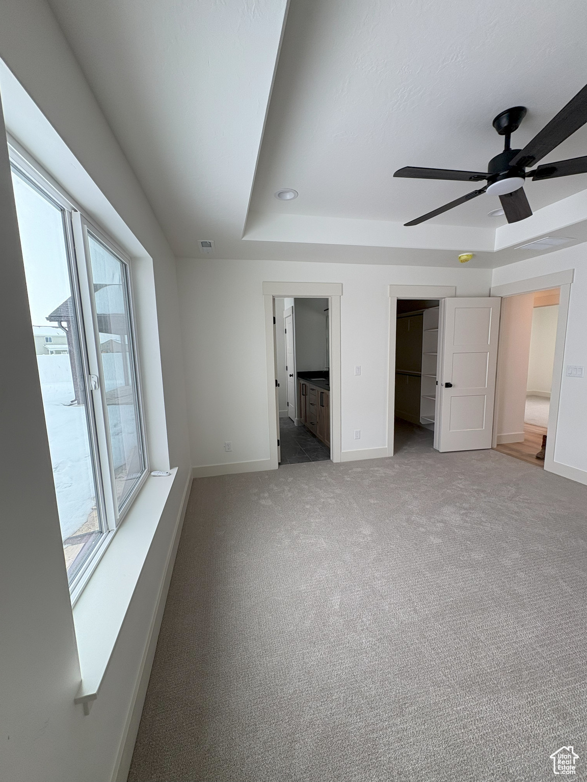 Unfurnished bedroom featuring visible vents, a raised ceiling, connected bathroom, carpet, and baseboards