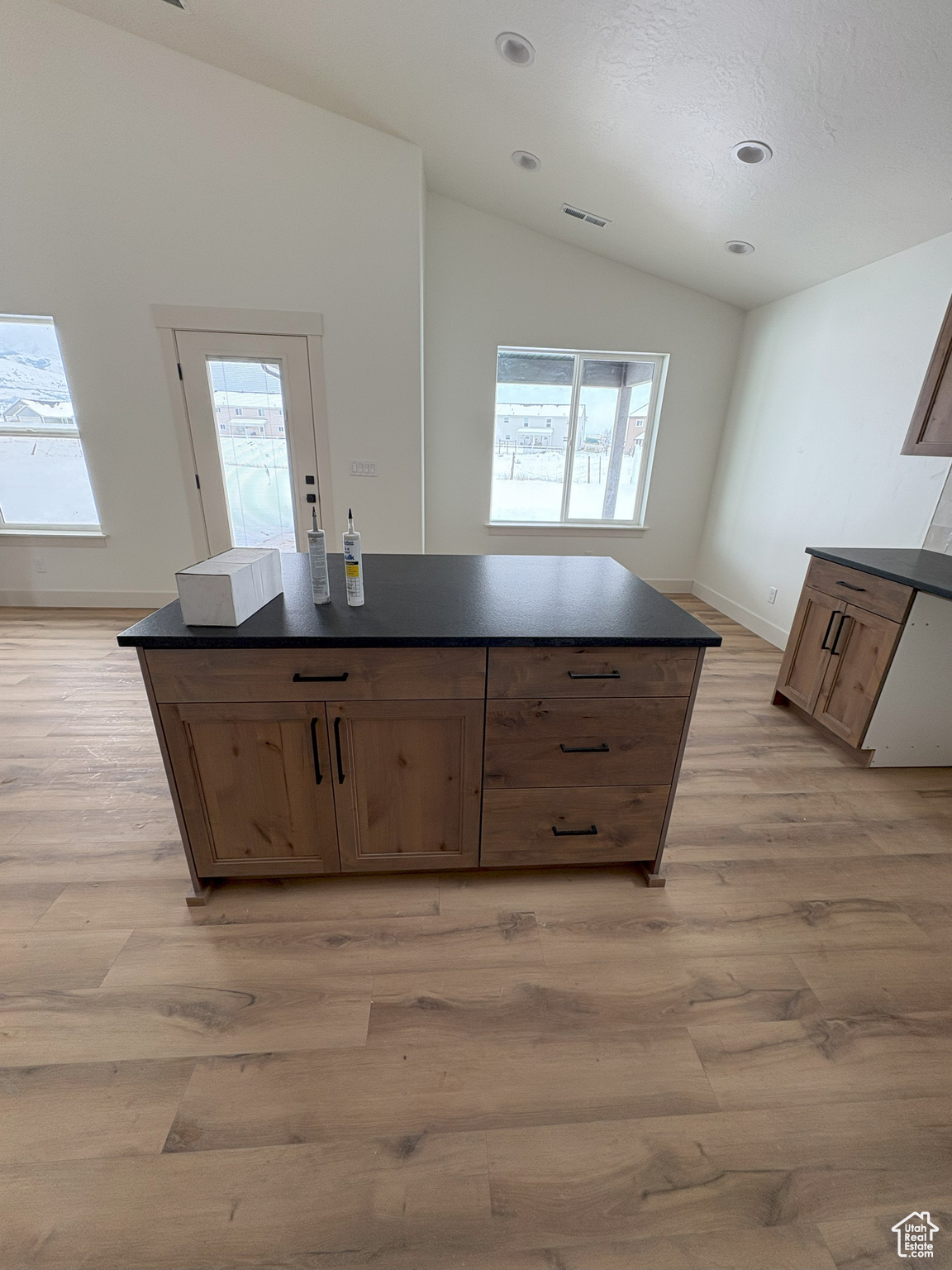 Kitchen featuring dark countertops, visible vents, a kitchen island, and lofted ceiling