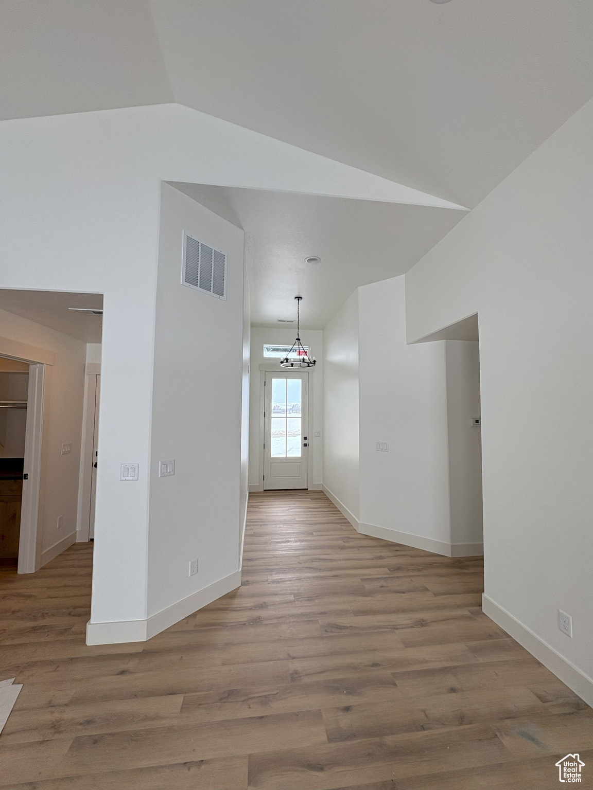 Unfurnished room with vaulted ceiling, baseboards, visible vents, and light wood finished floors