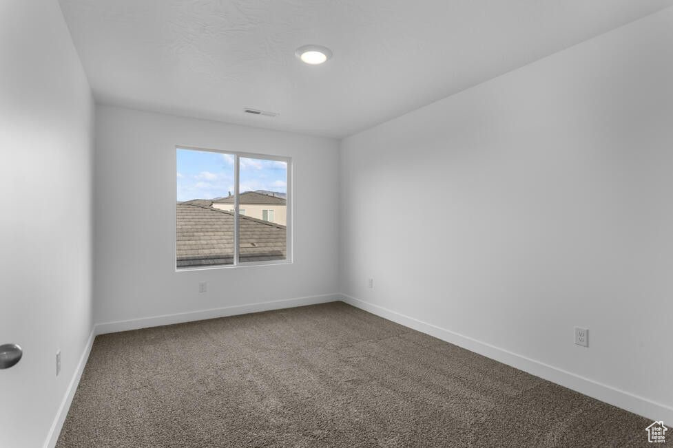 Carpeted empty room featuring visible vents and baseboards