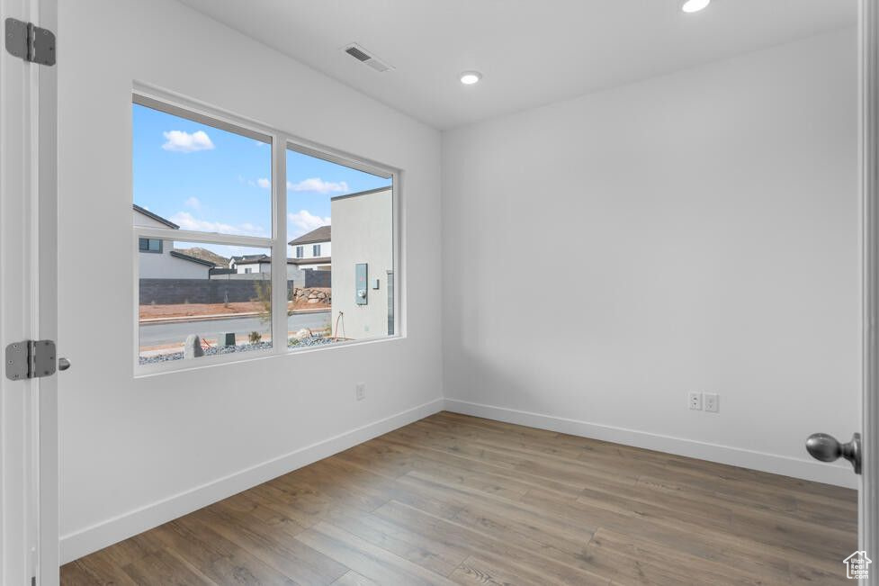 Unfurnished room with visible vents, wood finished floors, and baseboards