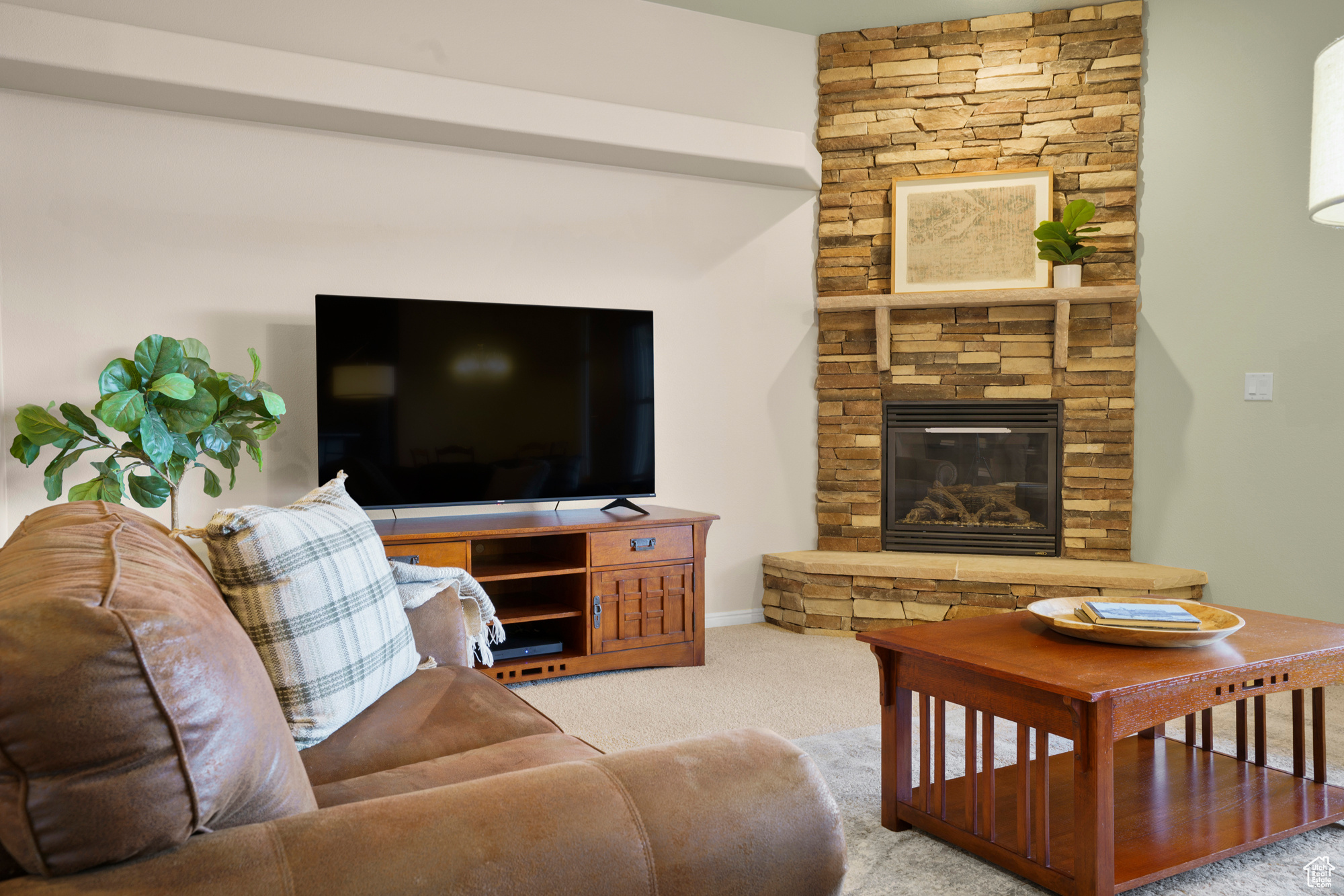 Carpeted living area featuring a stone fireplace
