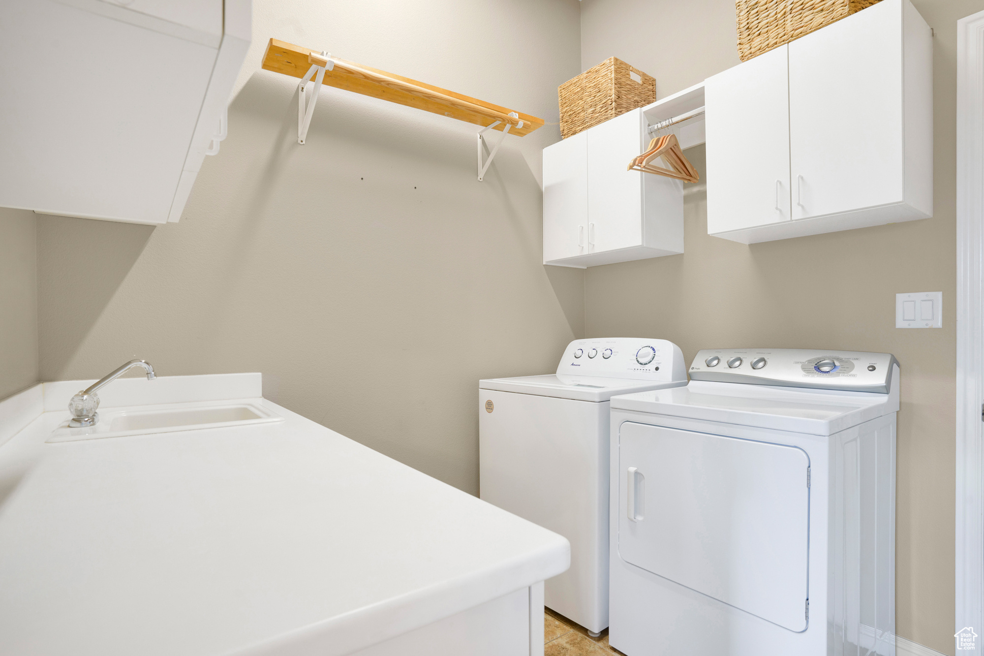 Clothes washing area featuring a sink, cabinet space, and separate washer and dryer