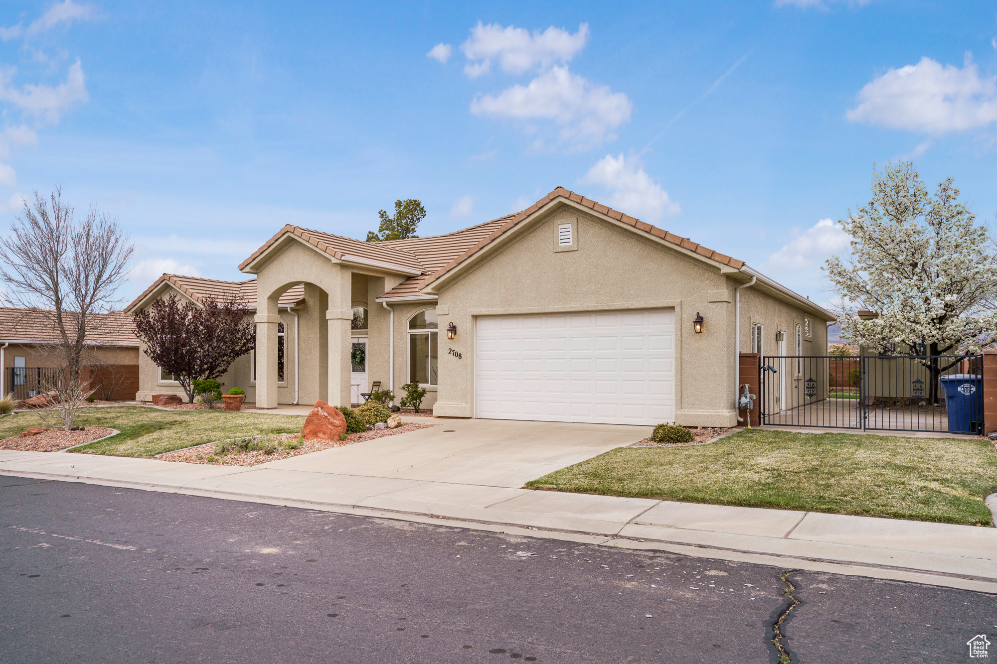 Mediterranean / spanish home with stucco siding, an attached garage, a front yard, and fence