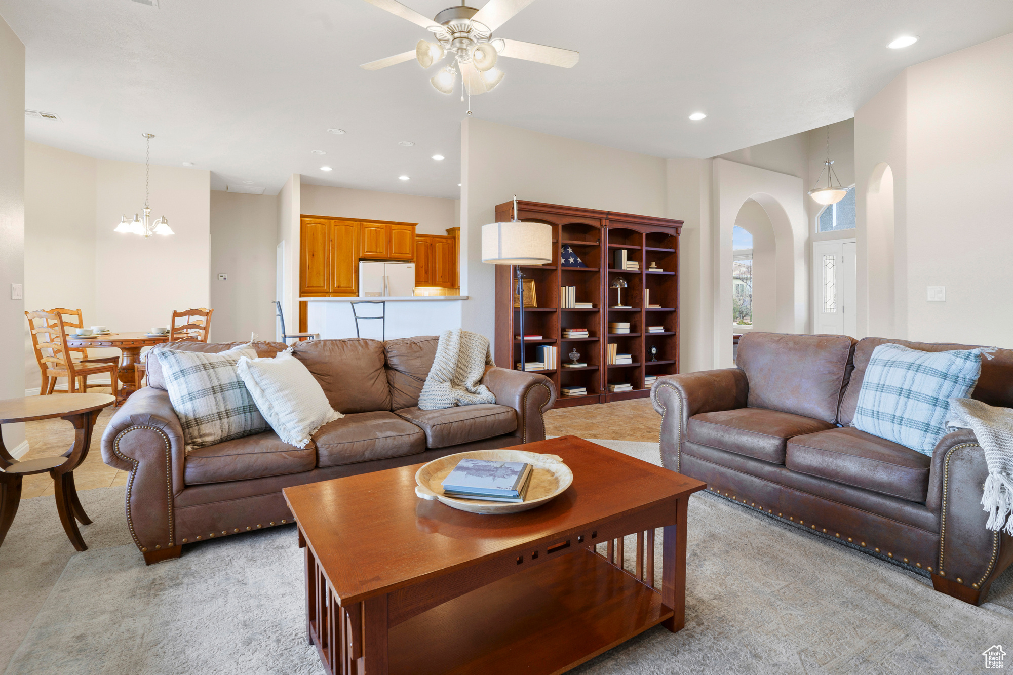 Living room featuring ceiling fan with notable chandelier, recessed lighting, arched walkways, and light colored carpet