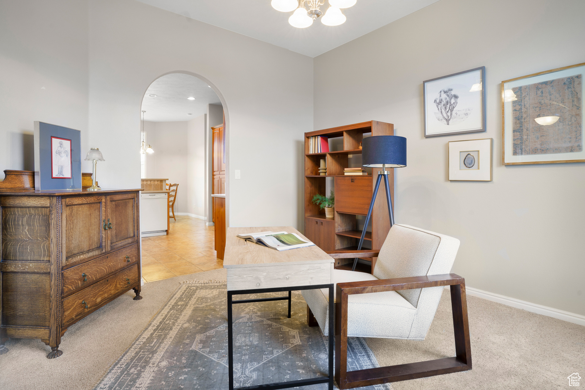 Office with arched walkways, a chandelier, light carpet, and baseboards