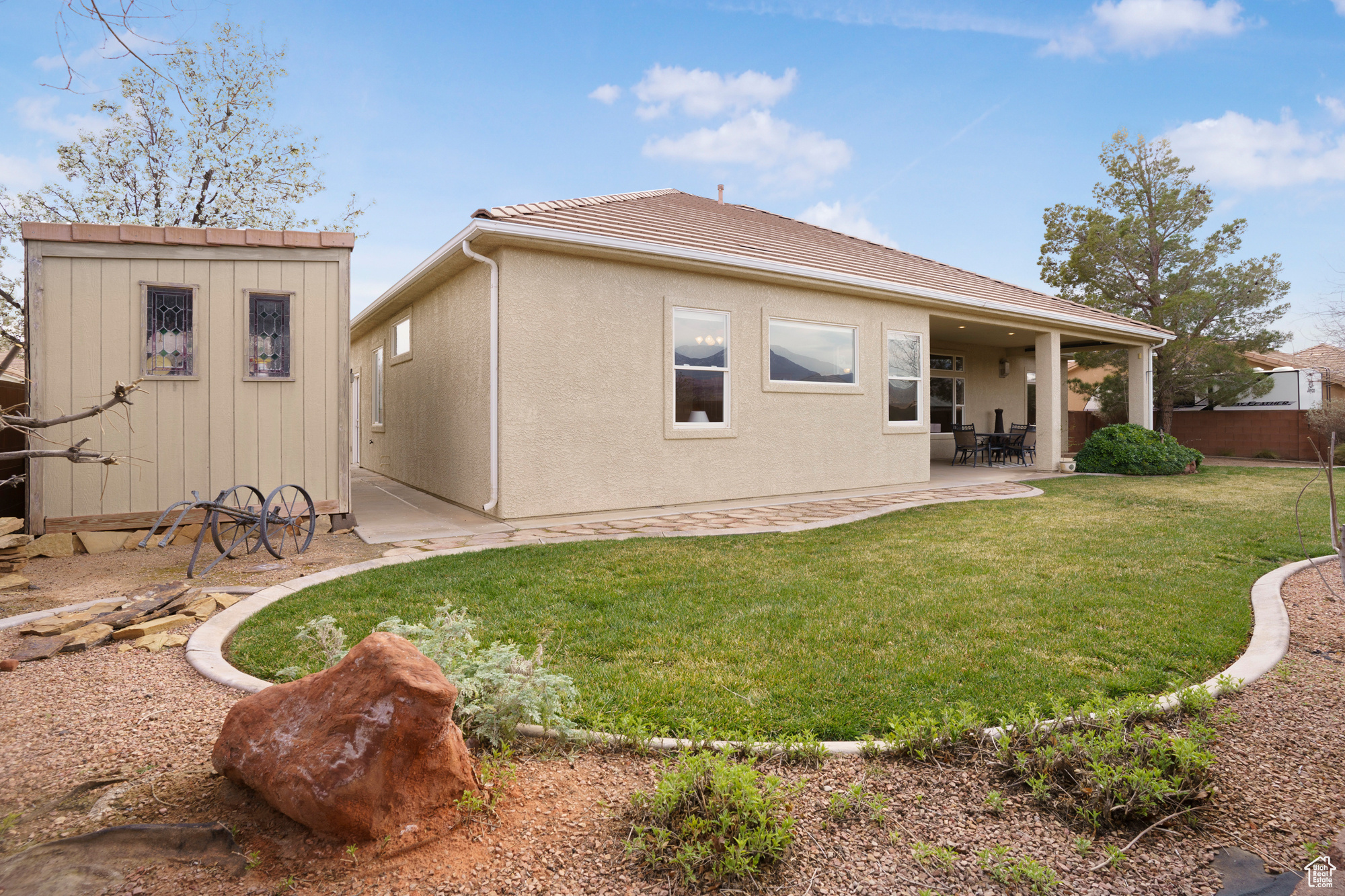 Rear view of house with an outdoor structure, a storage unit, a tiled roof, a patio area, and a lawn