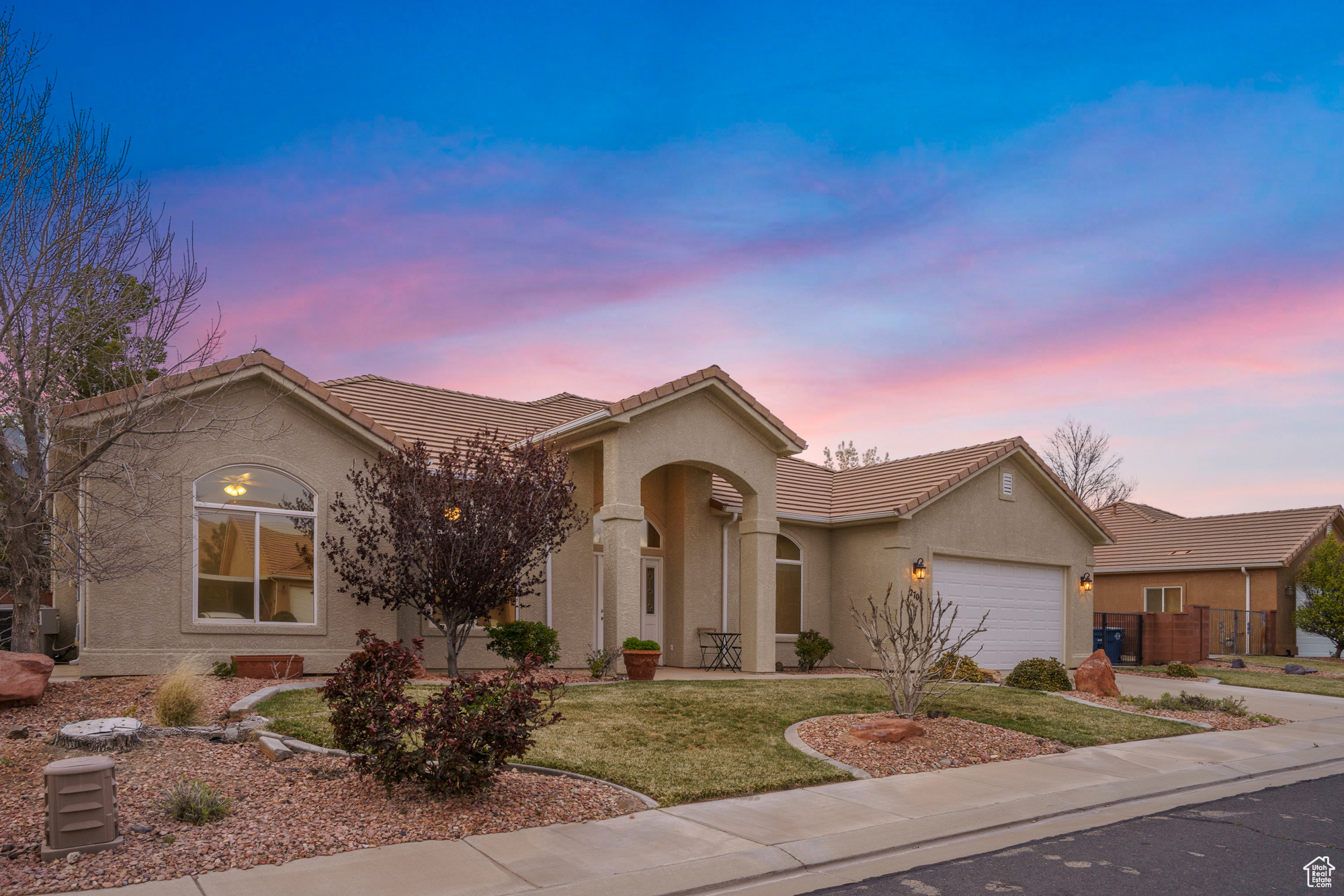 Ranch-style home with stucco siding, driveway, a tile roof, a yard, and a garage