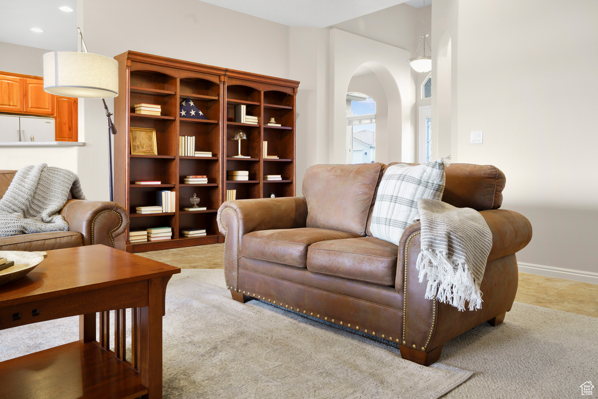 Living room with recessed lighting, baseboards, arched walkways, and light colored carpet