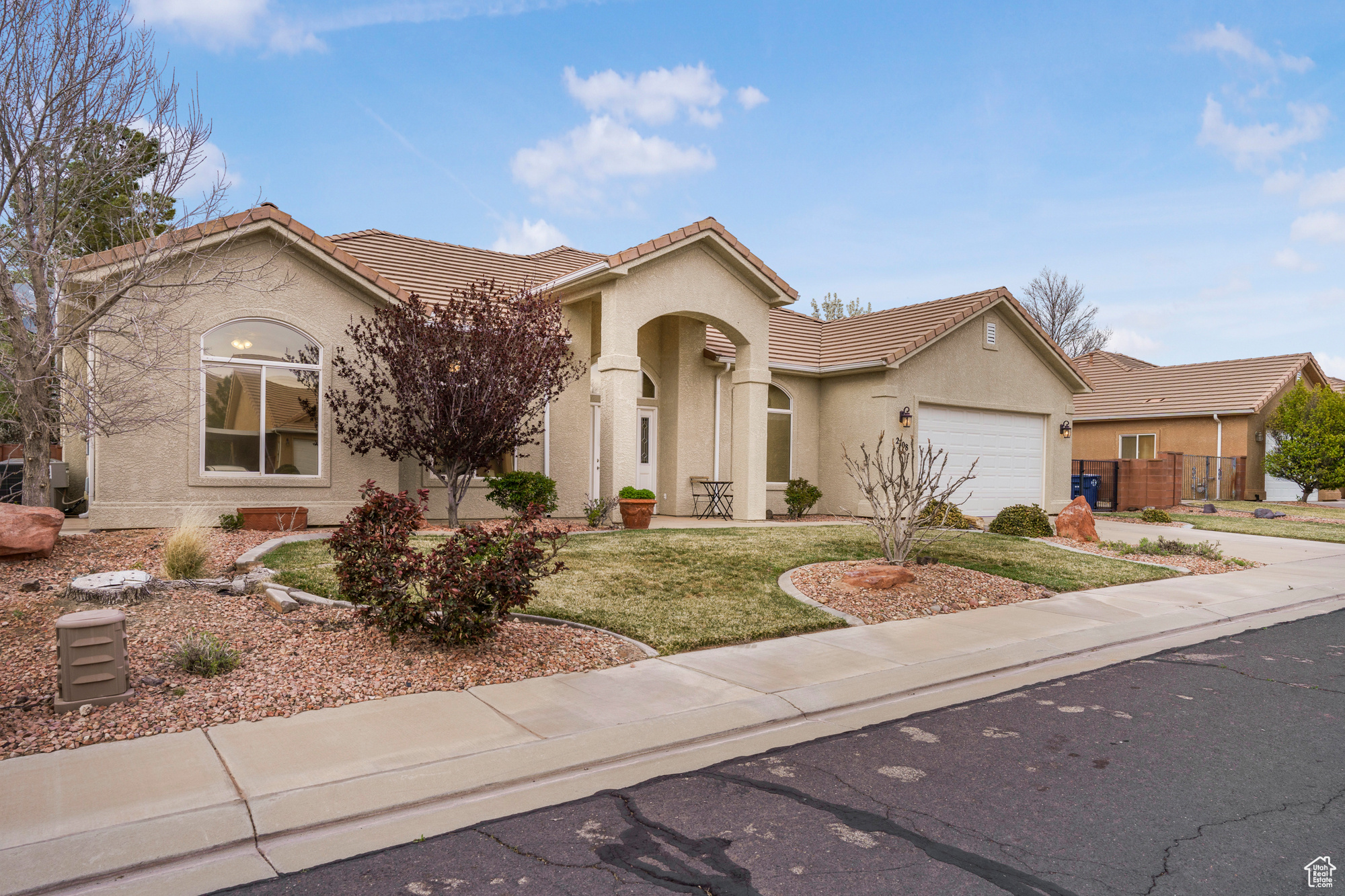 Mediterranean / spanish-style house featuring stucco siding, a tile roof, concrete driveway, a front yard, and an attached garage