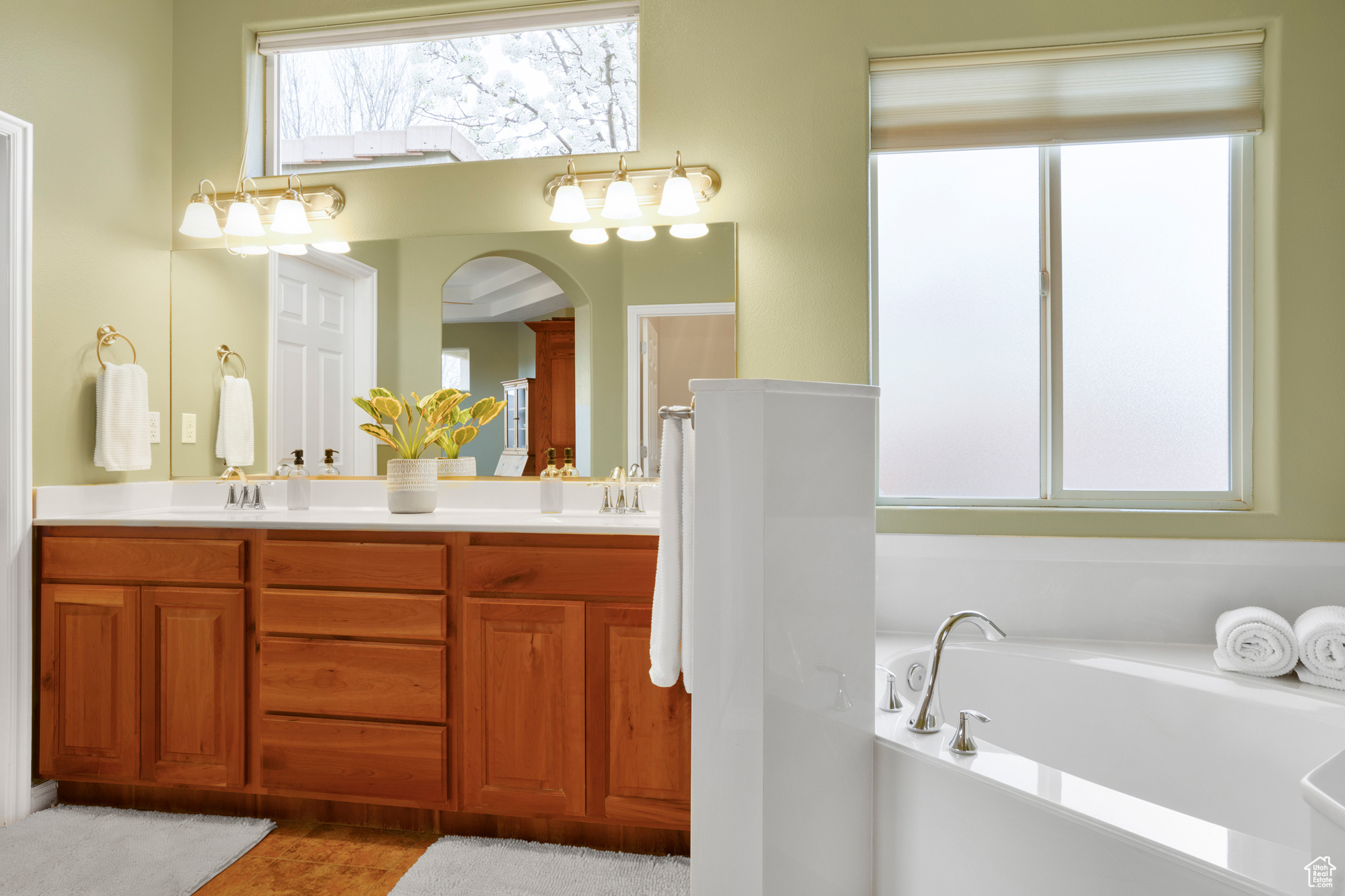 Full bathroom featuring a garden tub, double vanity, and a sink