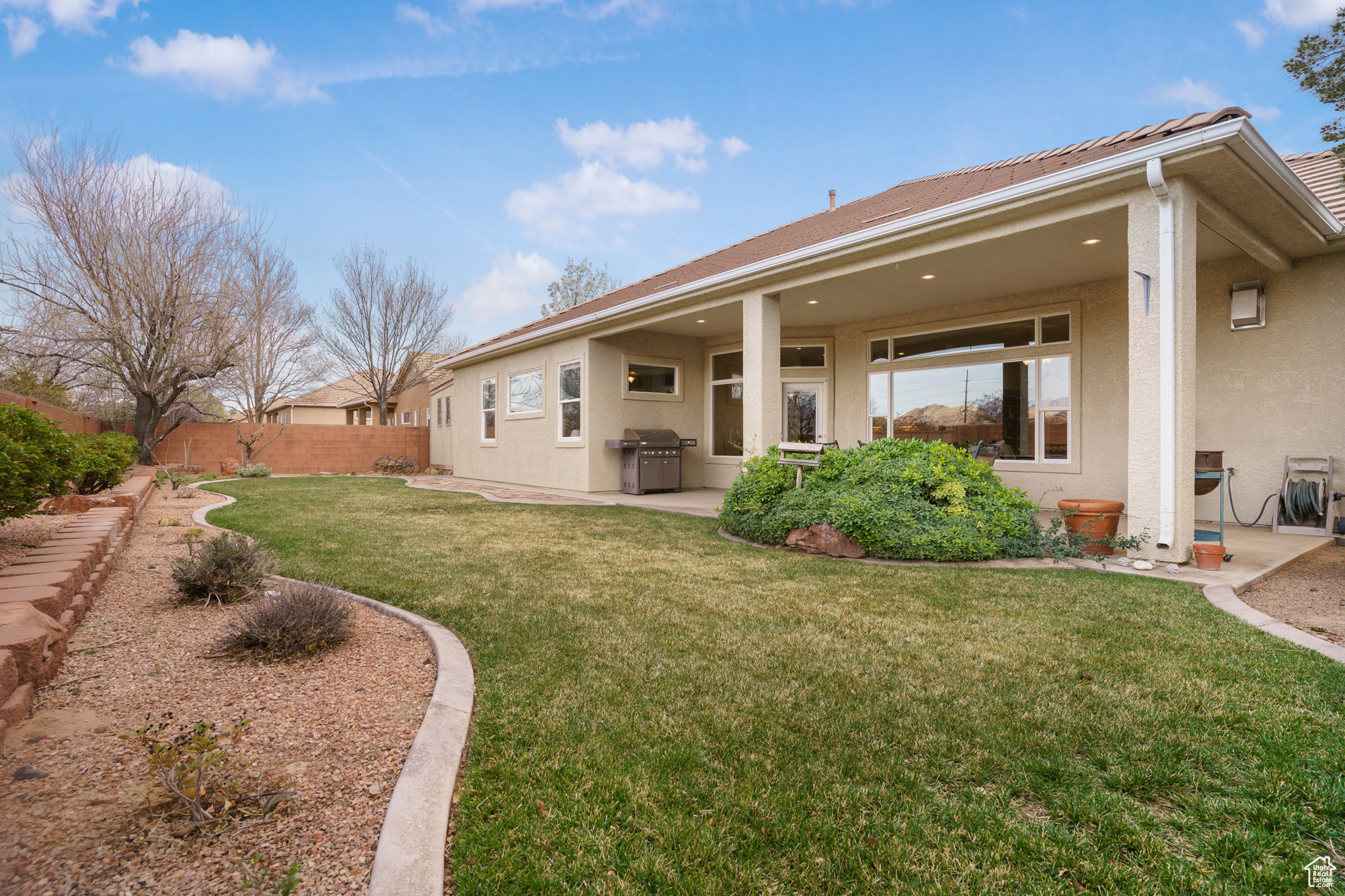 Back of property with stucco siding, a lawn, a fenced backyard, and a patio area