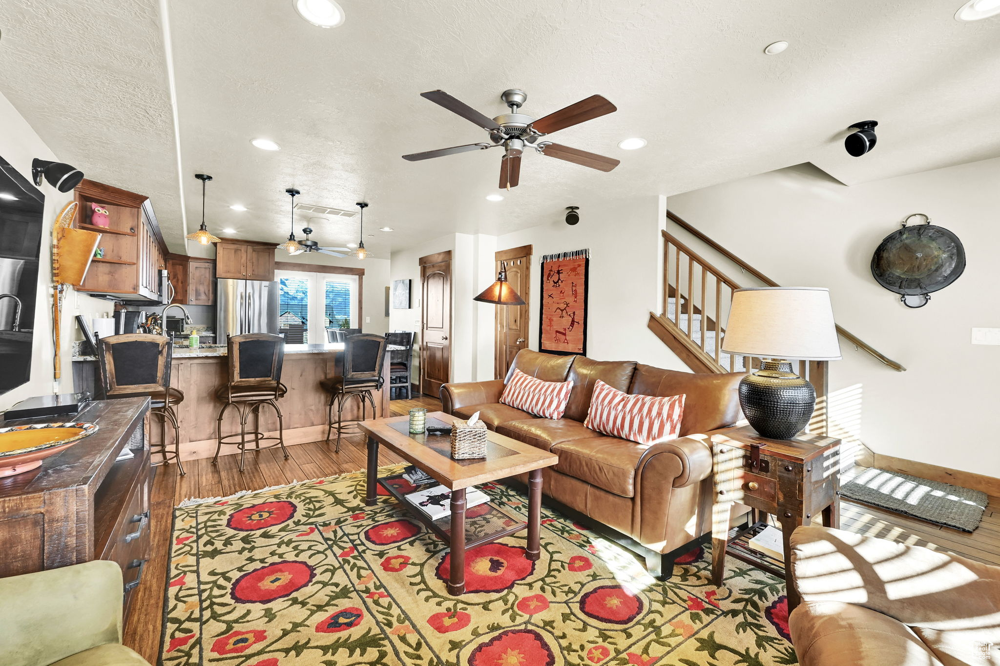 Living room featuring a ceiling fan, baseboards, recessed lighting, light wood-style floors, and a textured ceiling