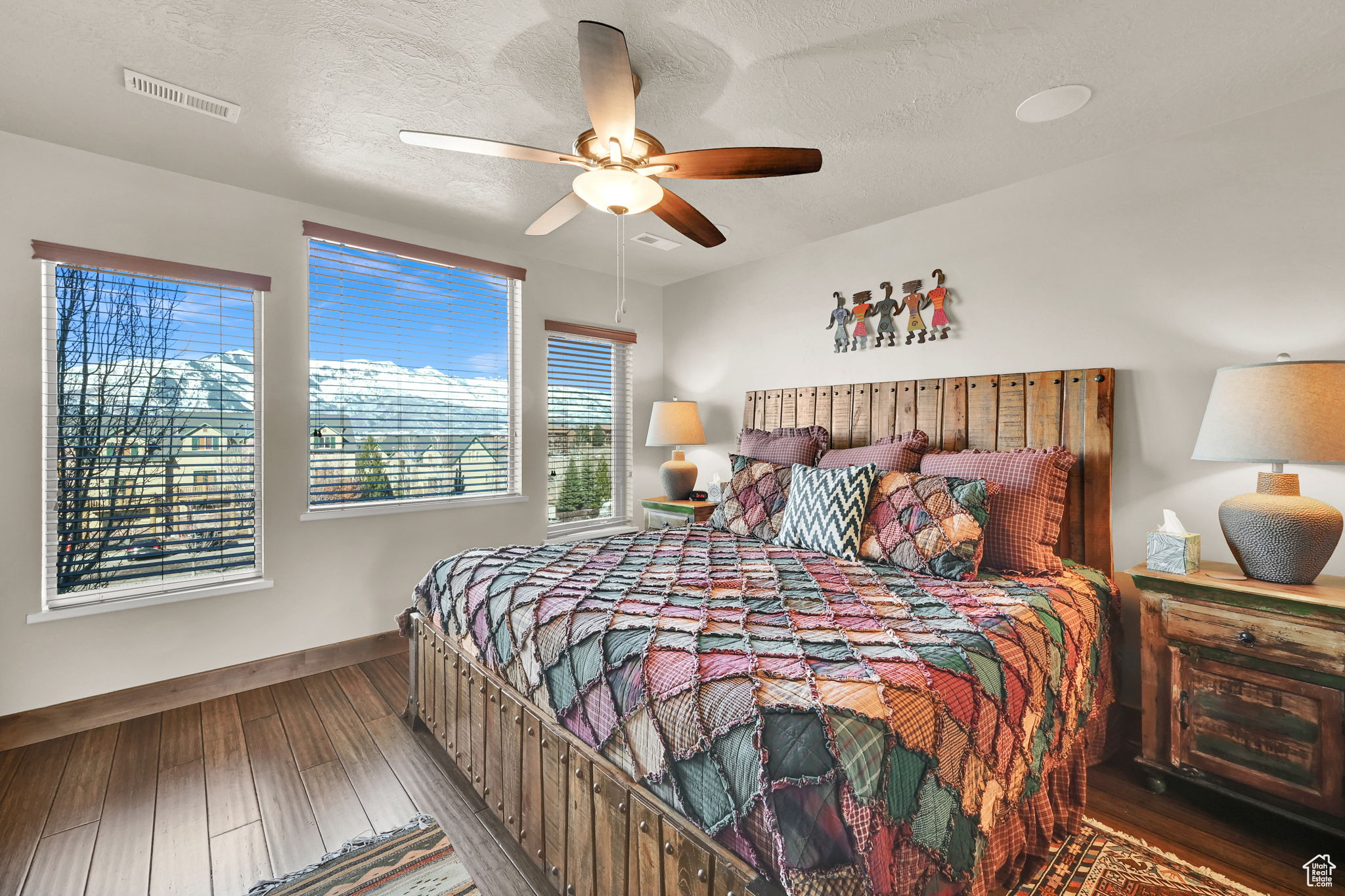 Bedroom with visible vents, a ceiling fan, a textured ceiling, wood-type flooring, and baseboards