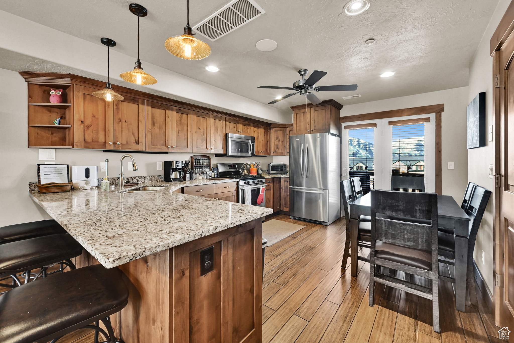 Kitchen featuring visible vents, a peninsula, a sink, stainless steel appliances, and light wood-style floors