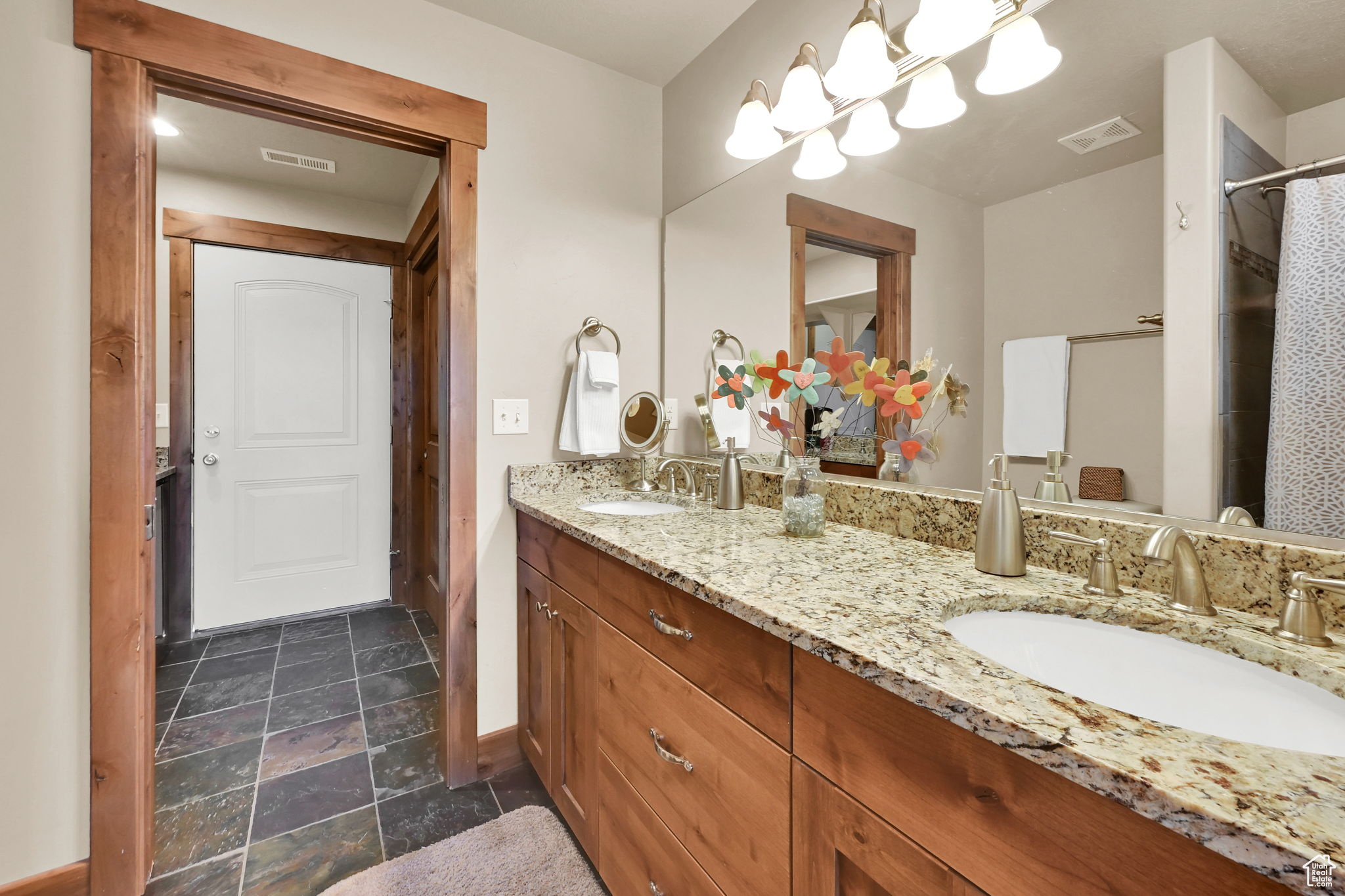 Full bath featuring a sink, visible vents, double vanity, and stone finish floor