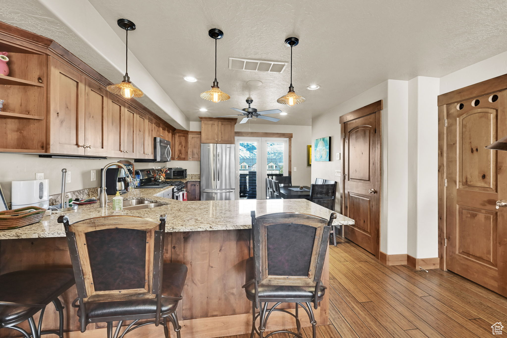 Kitchen with visible vents, a sink, stainless steel appliances, light wood-style floors, and a peninsula