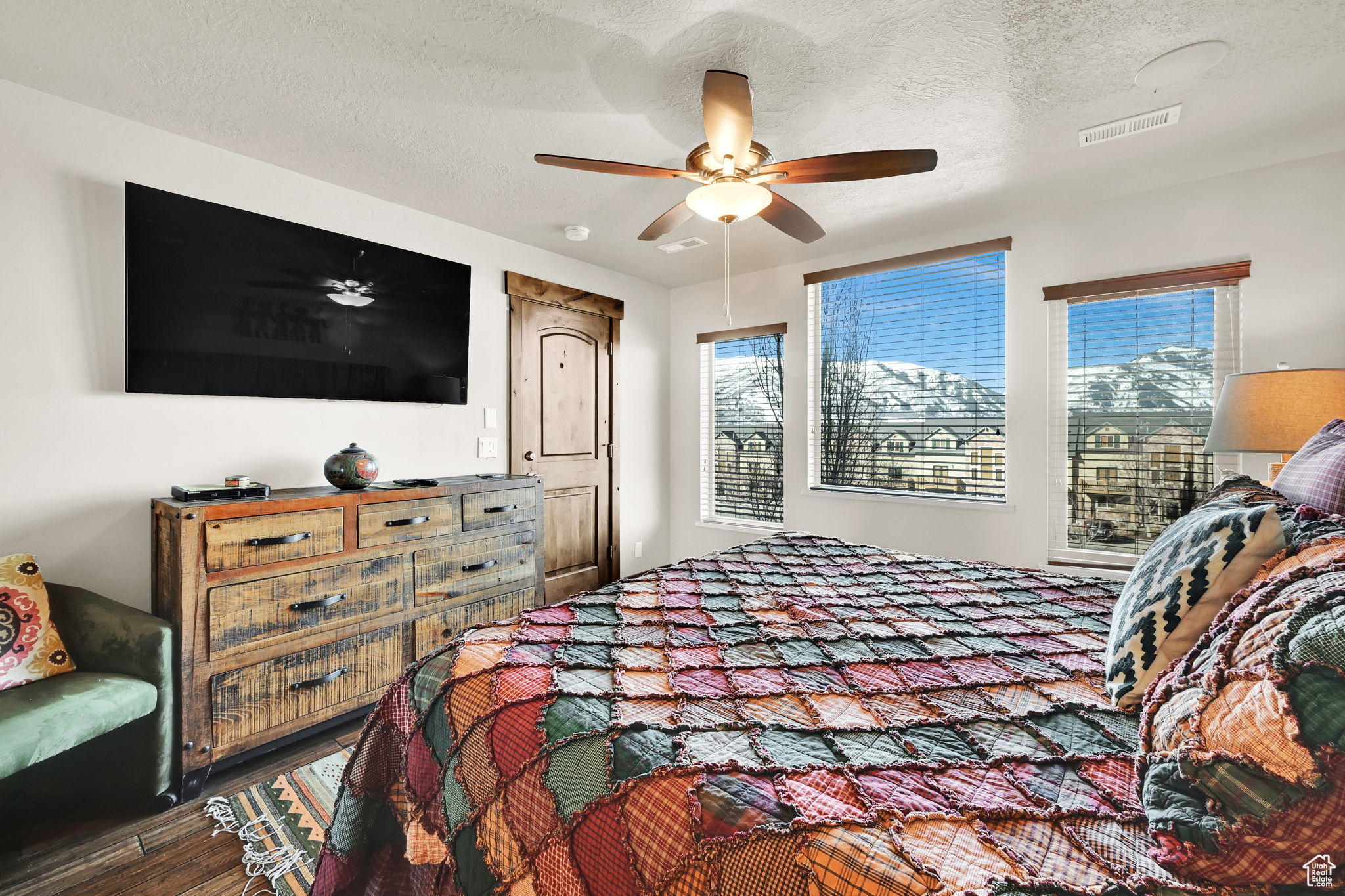 Bedroom with visible vents, multiple windows, a textured ceiling, and wood finished floors