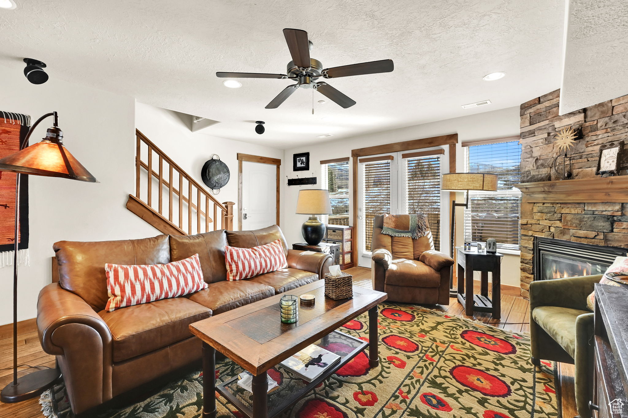 Living room featuring a fireplace, stairway, wood finished floors, and a textured ceiling