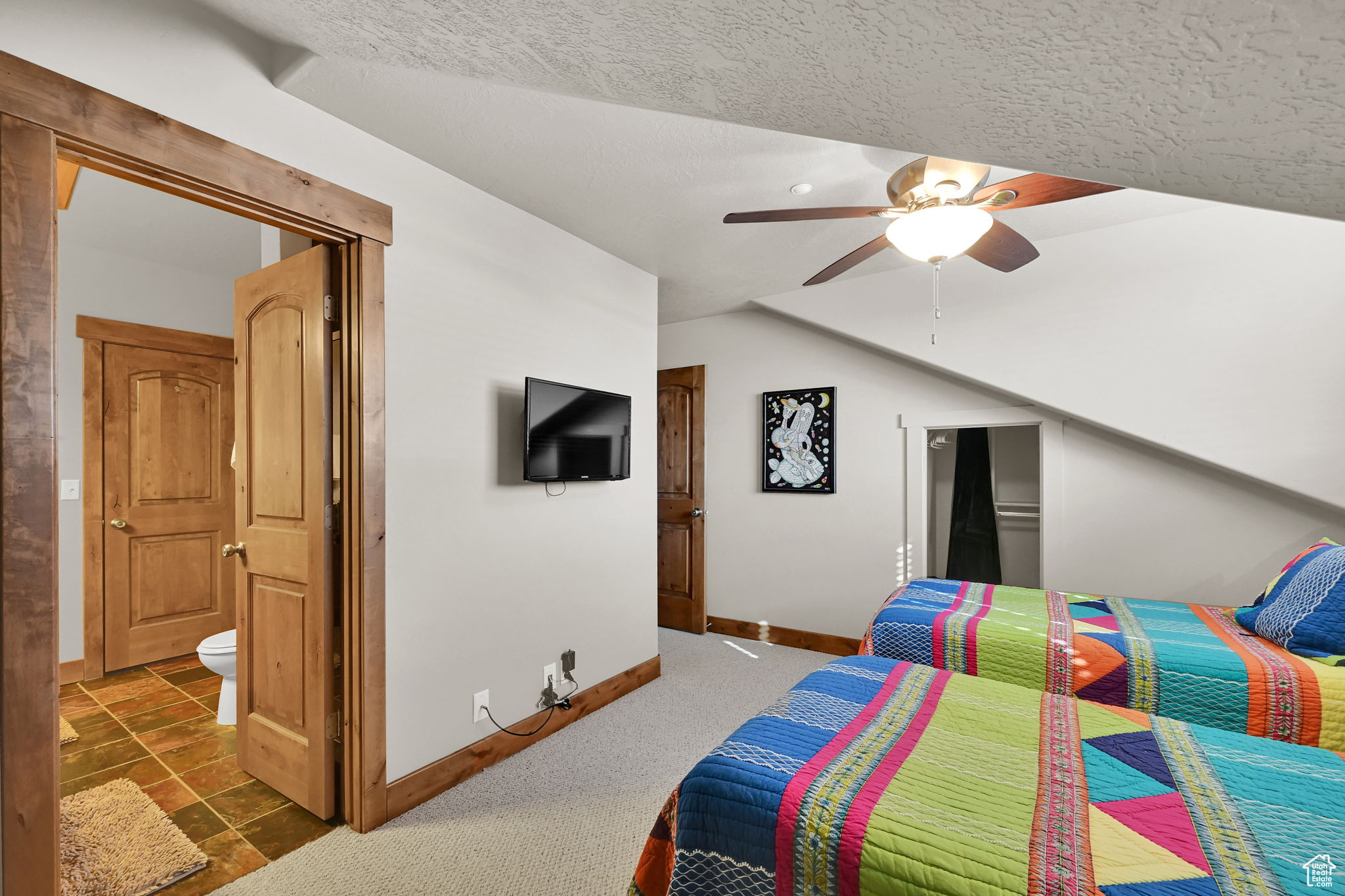 Bedroom featuring ceiling fan, ensuite bath, baseboards, and a textured ceiling