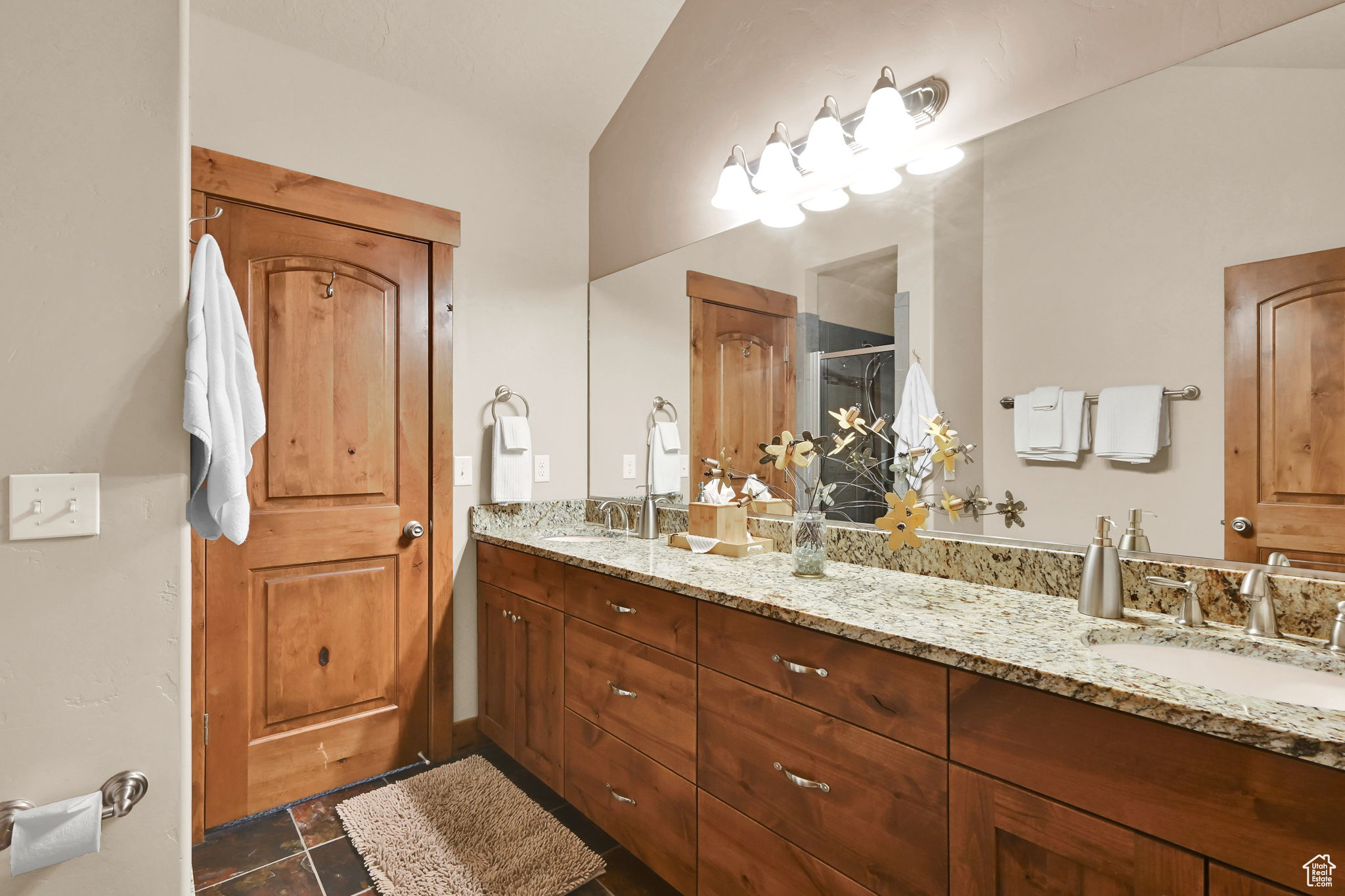 Bathroom featuring a sink, a stall shower, double vanity, and tile patterned floors