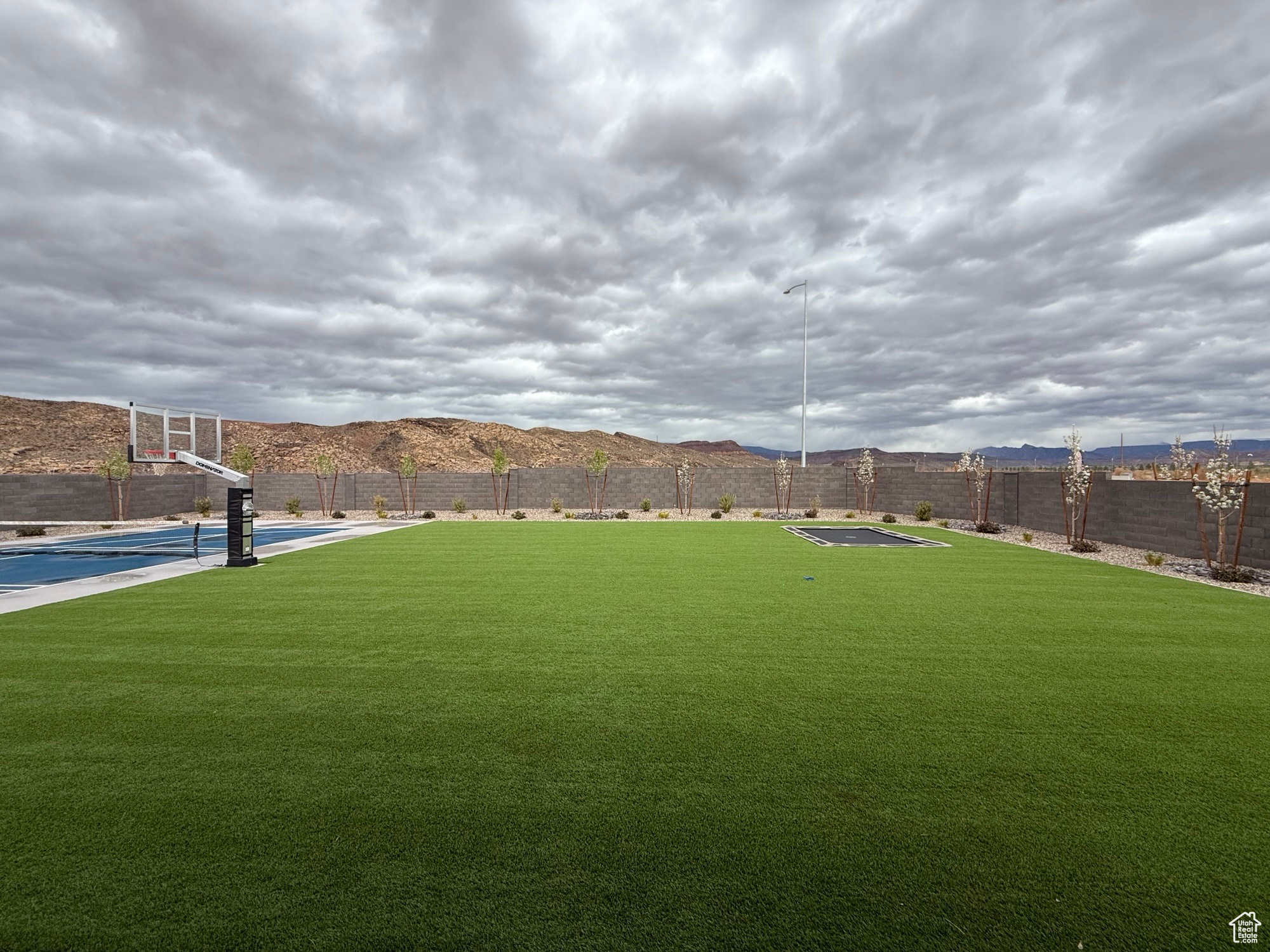 View of yard with a mountain view, community basketball court, and fence