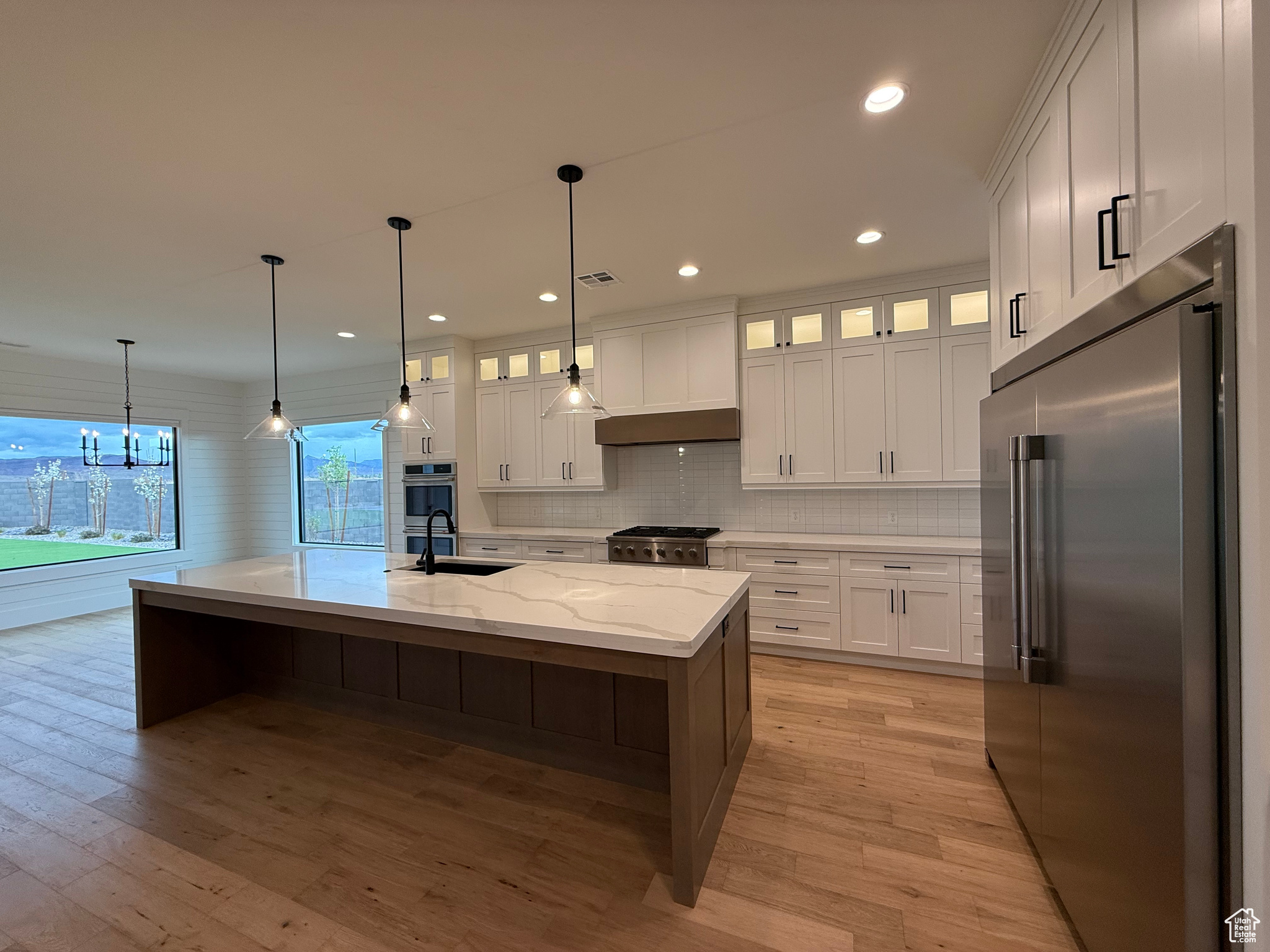 Kitchen featuring light wood-style flooring, white cabinets, stainless steel appliances, and a sink