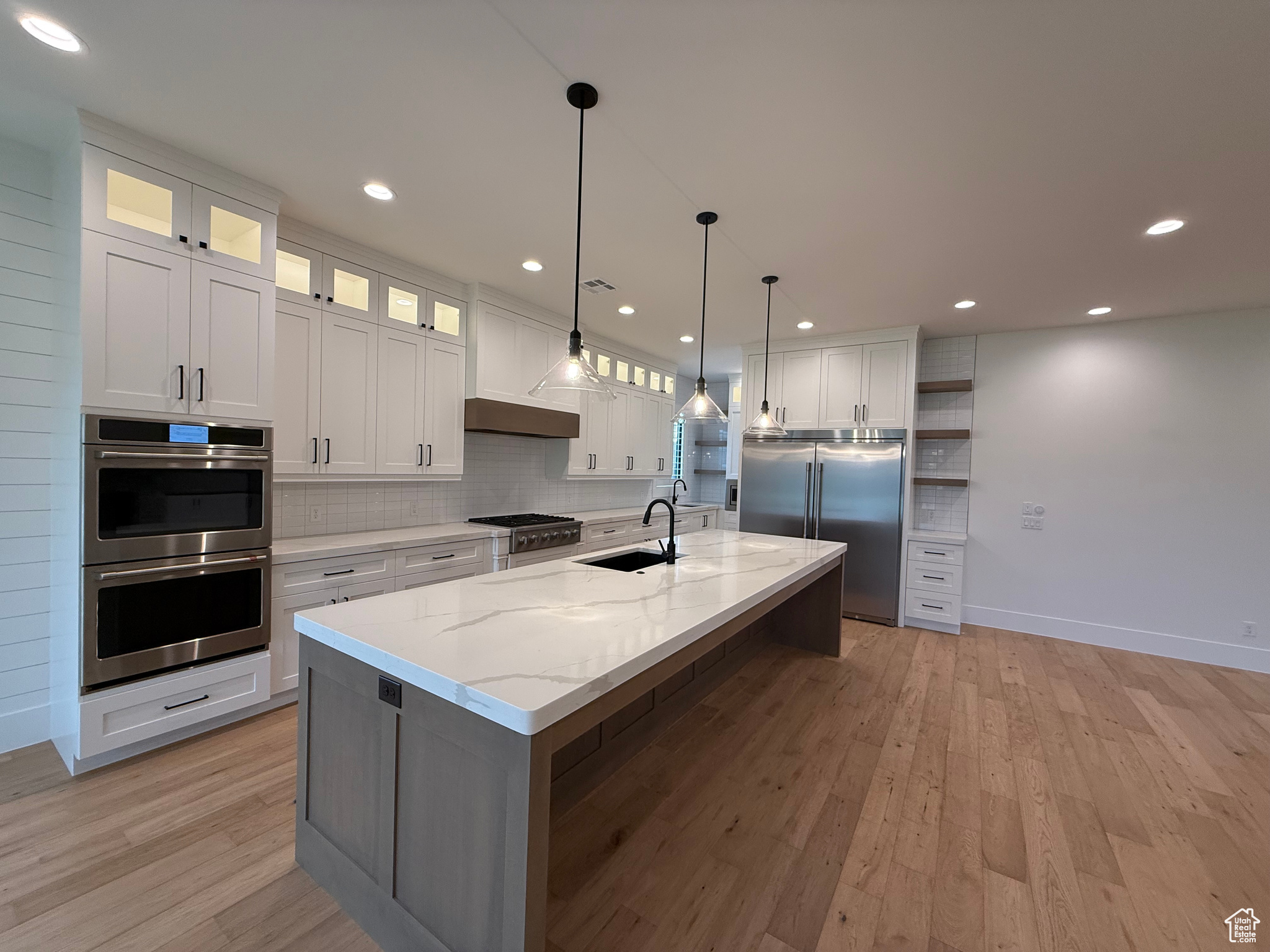 Kitchen with custom range hood, open shelves, a sink, stainless steel appliances, and decorative backsplash