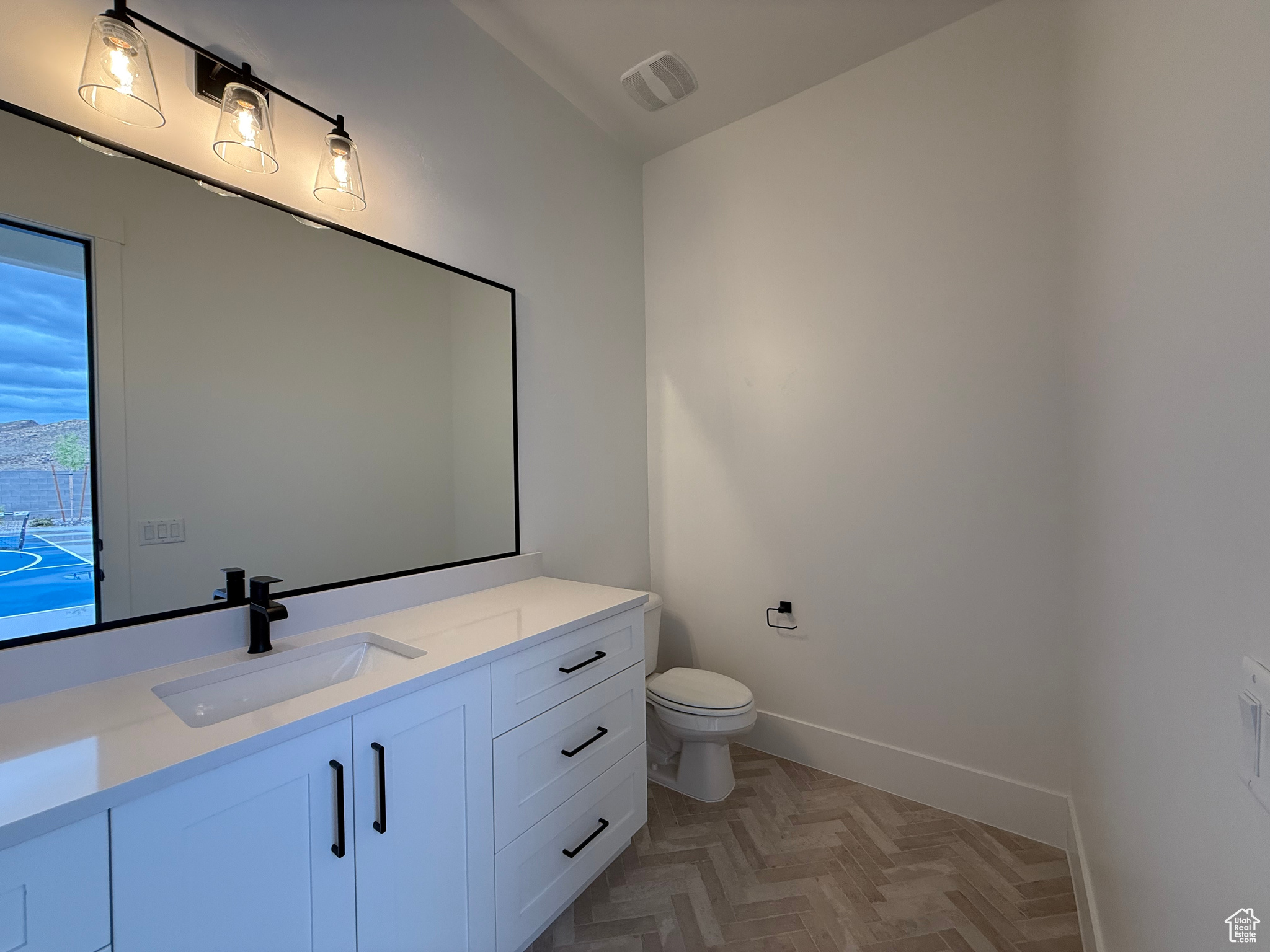 Bathroom with visible vents, toilet, vanity, and baseboards