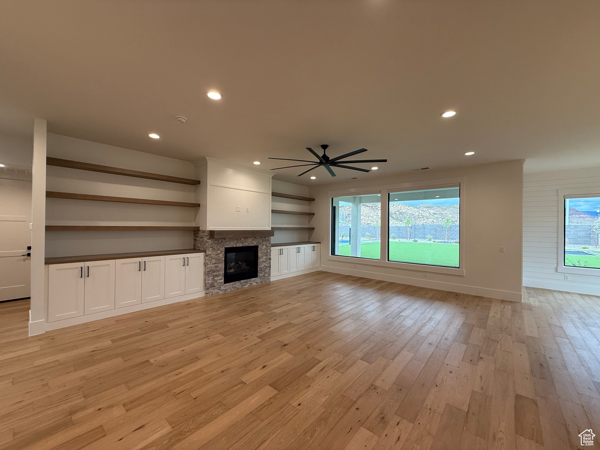 Unfurnished living room featuring recessed lighting, light wood-style flooring, a fireplace, and a ceiling fan