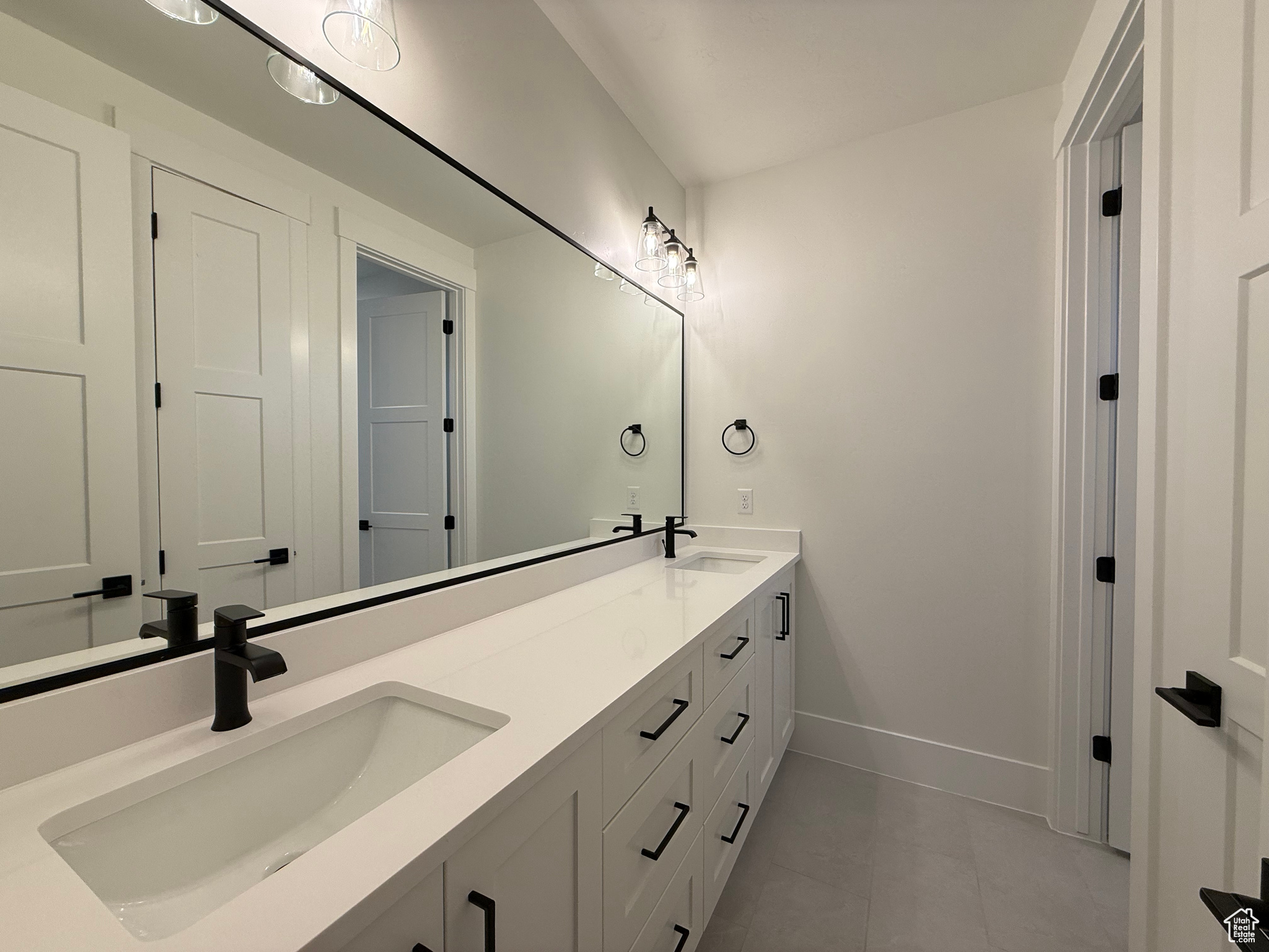 Full bath with a sink, baseboards, double vanity, and tile patterned flooring