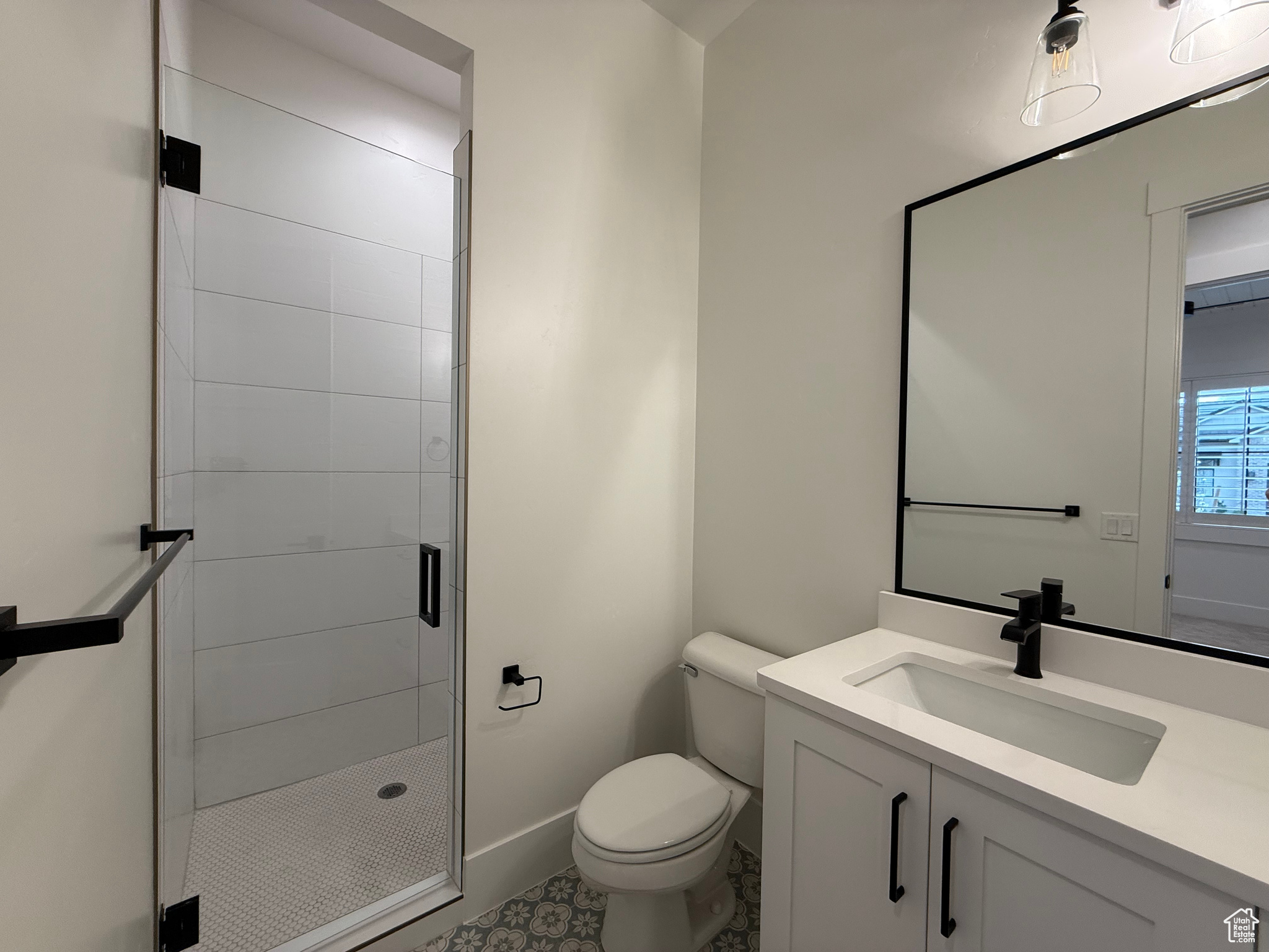 Bathroom with vanity, toilet, baseboards, and a stall shower