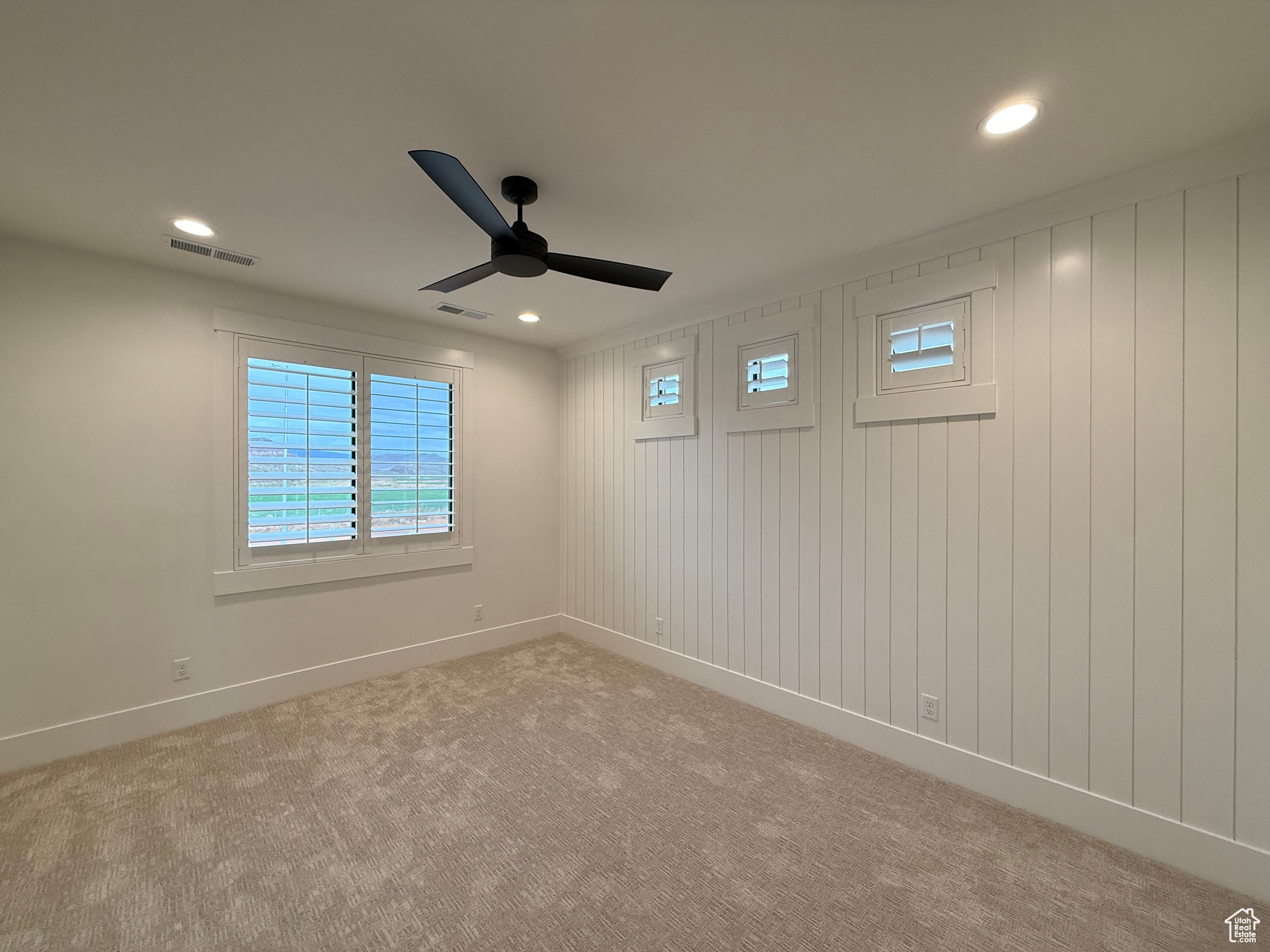 Unfurnished room featuring a ceiling fan, light colored carpet, visible vents, and baseboards