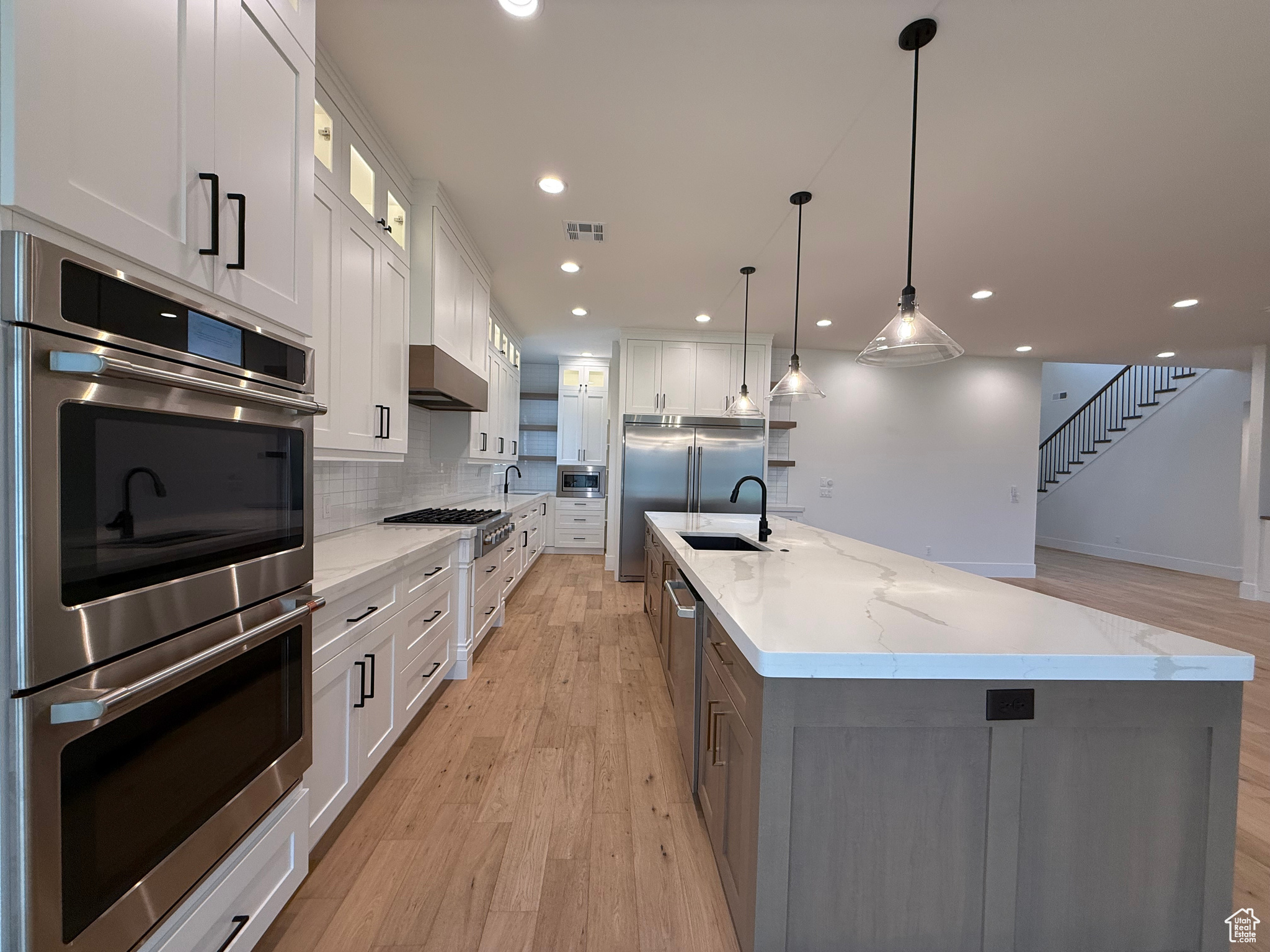 Kitchen featuring light wood-type flooring, visible vents, built in appliances, and a sink