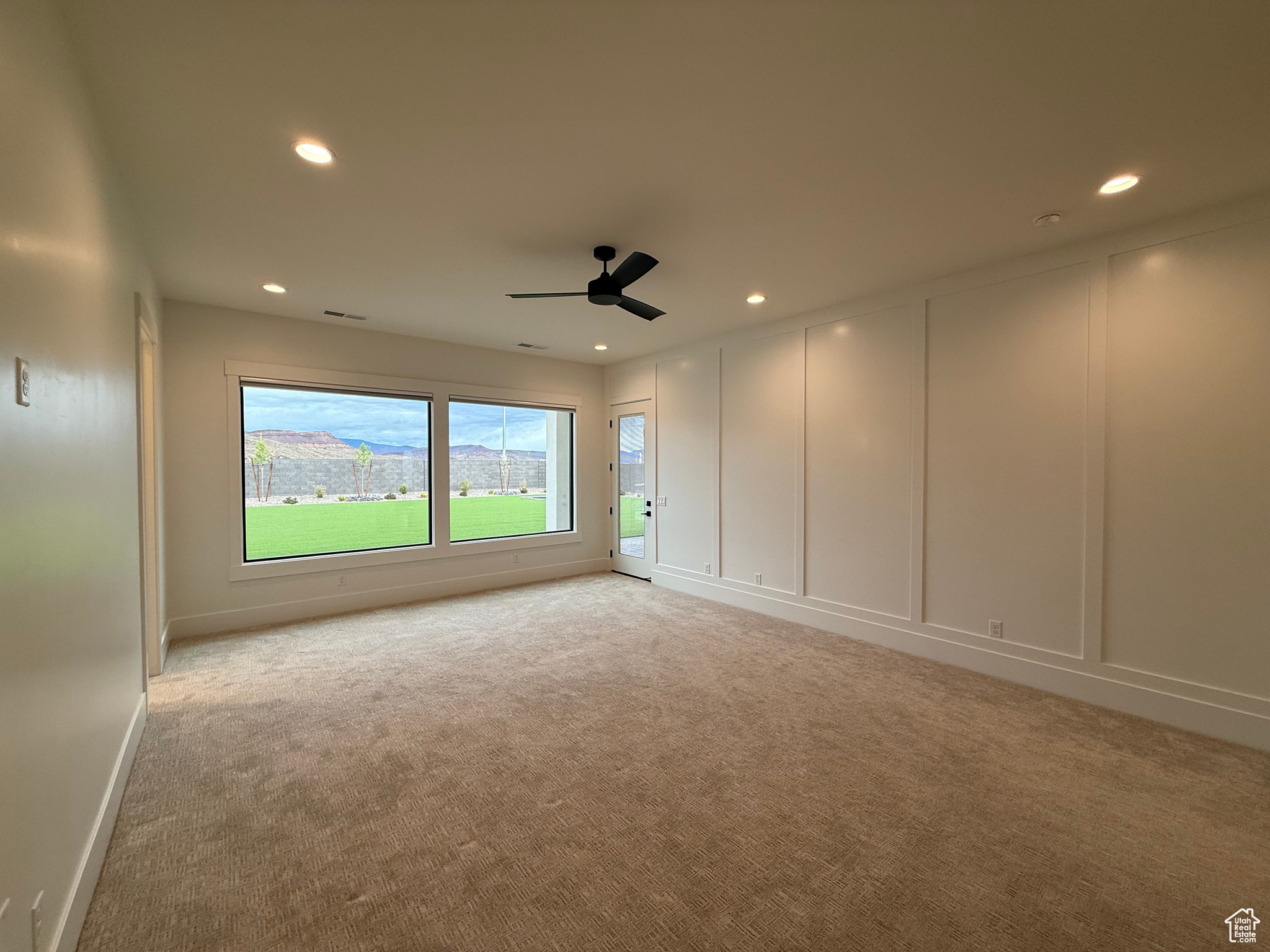 Empty room featuring visible vents, light carpet, recessed lighting, a decorative wall, and a ceiling fan