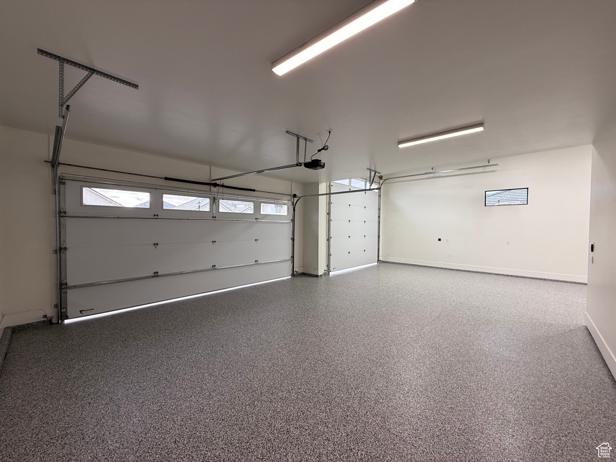 Garage featuring a garage door opener and baseboards