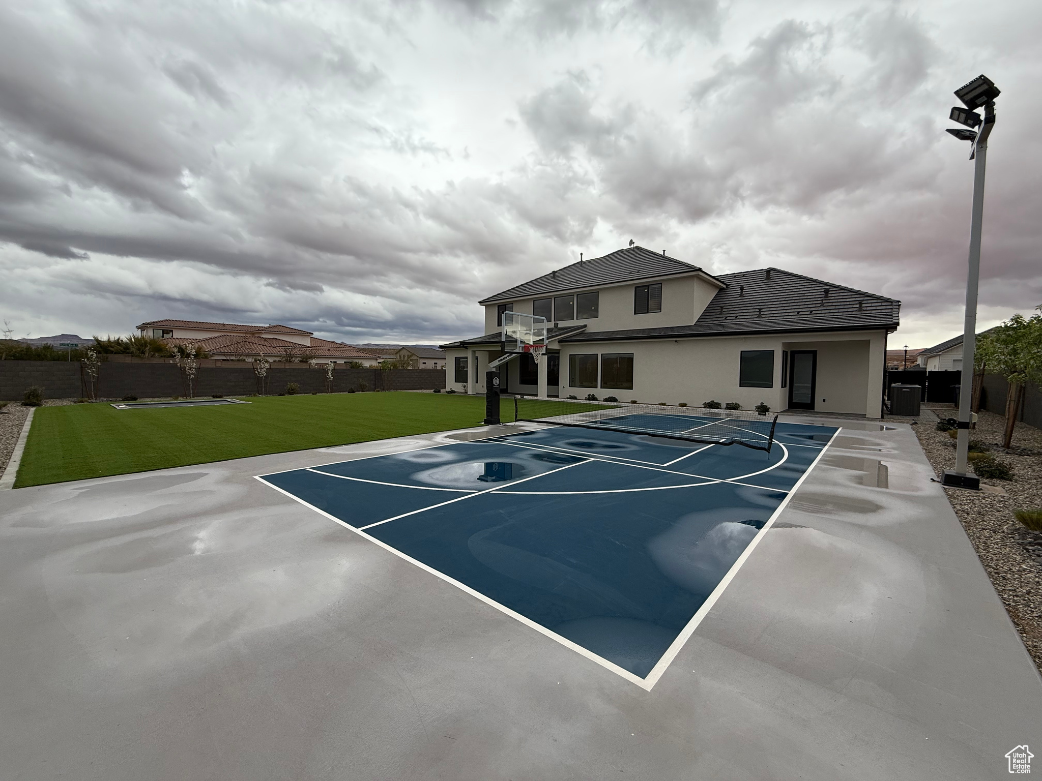 View of basketball court featuring basketball court, a yard, and fence