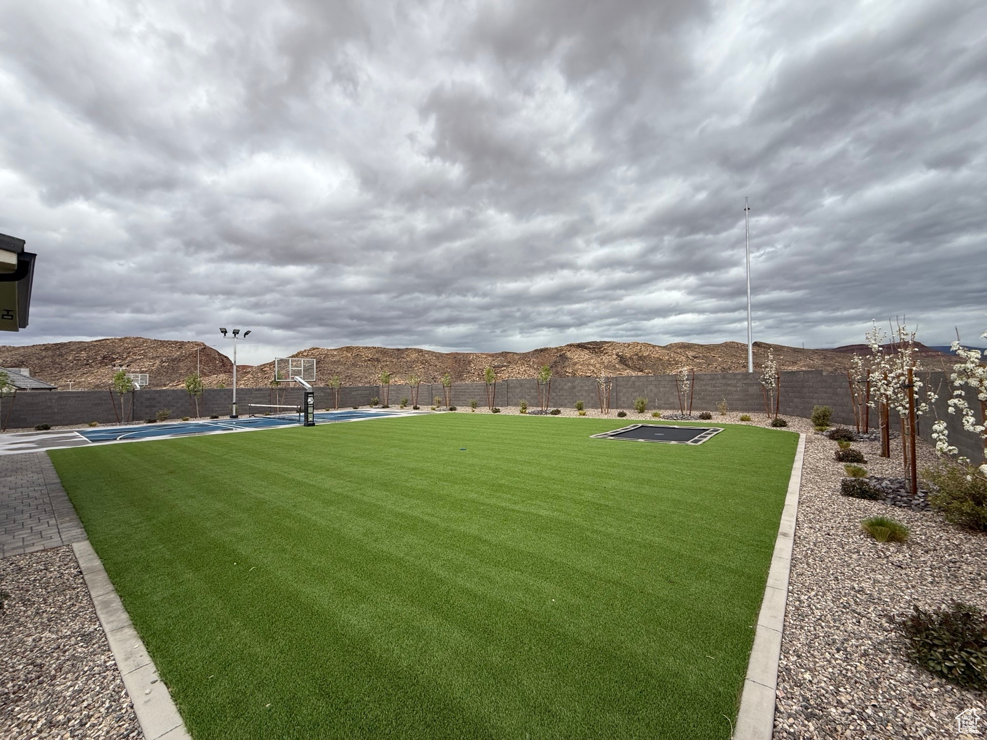 View of yard featuring a mountain view, a fenced backyard, and community basketball court