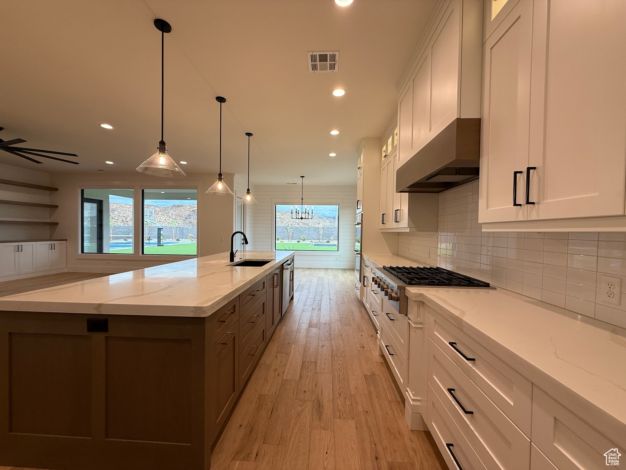 Kitchen with a sink, a large island, white cabinets, and stainless steel gas cooktop