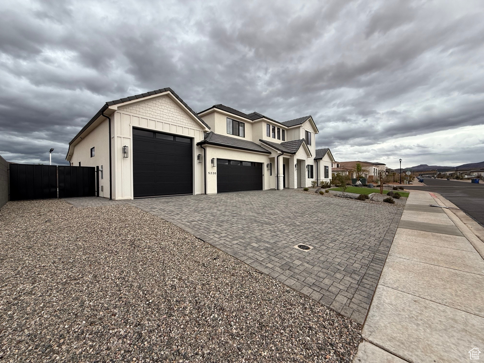 View of side of property featuring decorative driveway, an attached garage, and fence