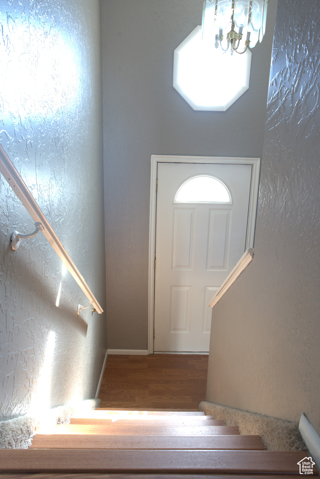 Foyer with a chandelier, a textured wall, and wood finished floors