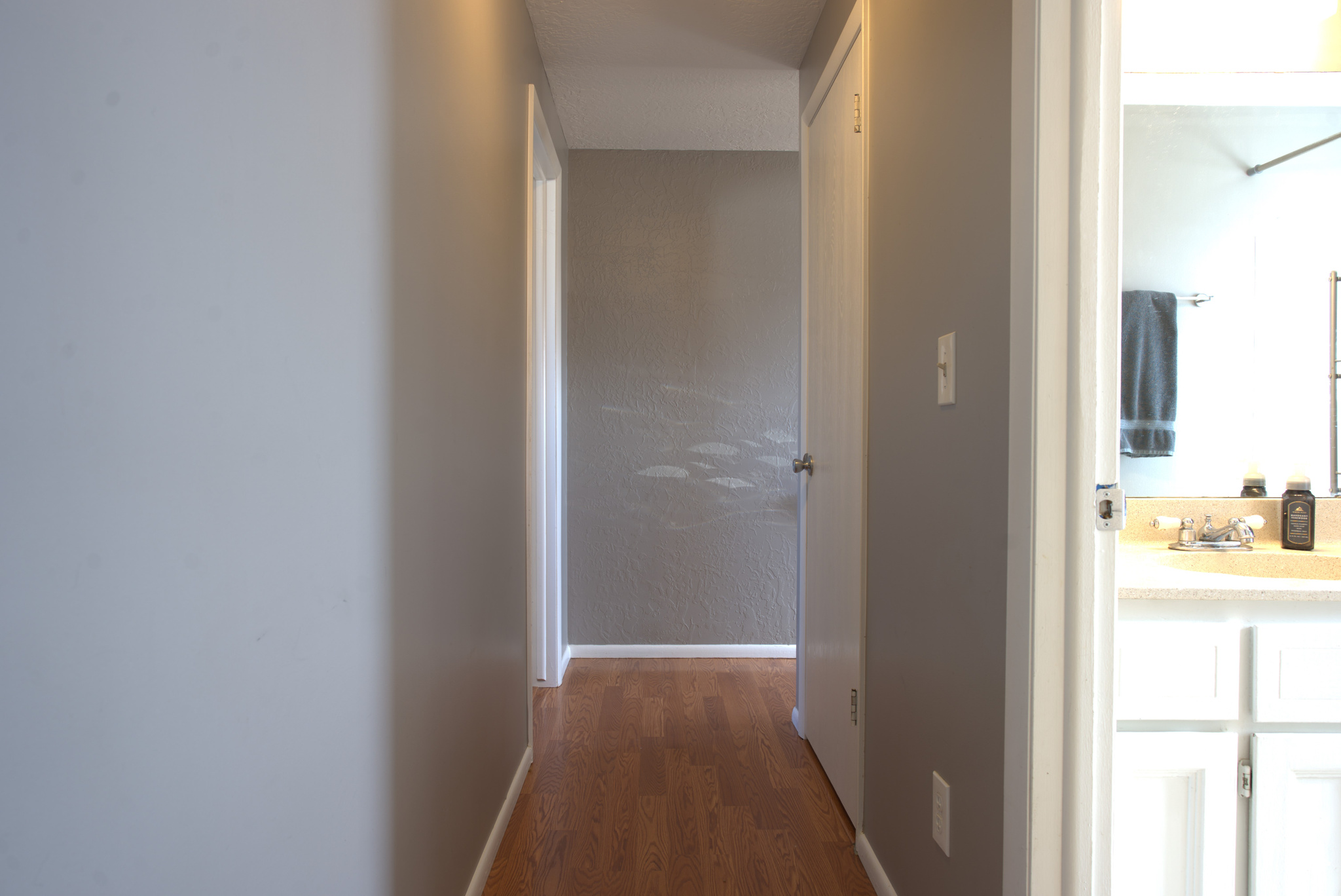 Hall with baseboards, dark wood-style flooring, and a sink