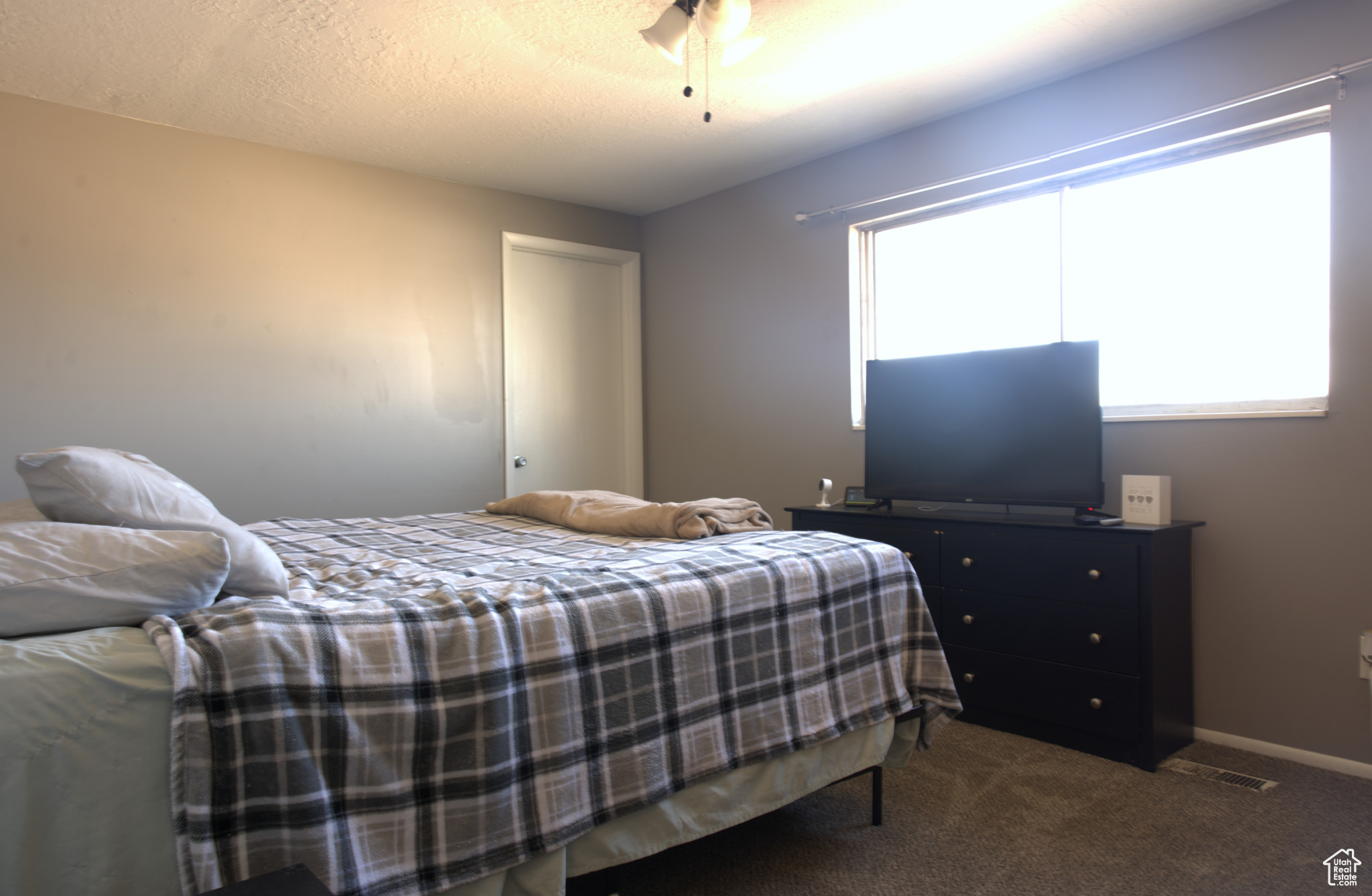 Carpeted bedroom featuring visible vents, ceiling fan, a textured ceiling, and baseboards