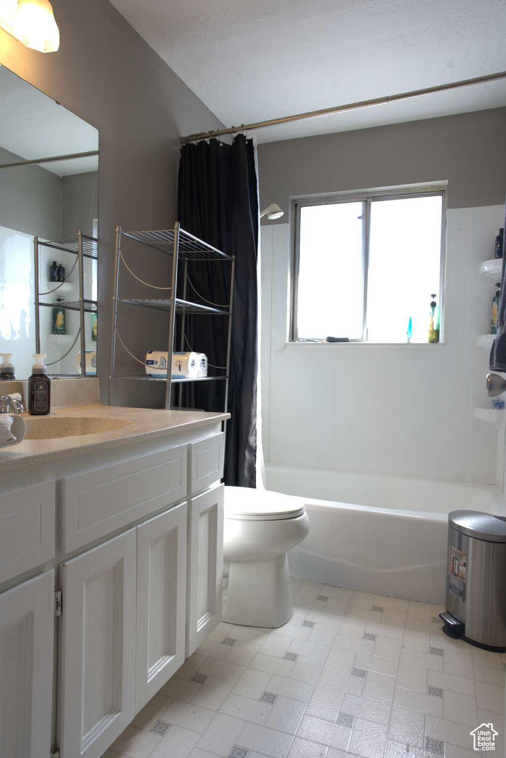 Full bath with vanity, tile patterned floors, toilet, and shower / tub combo with curtain