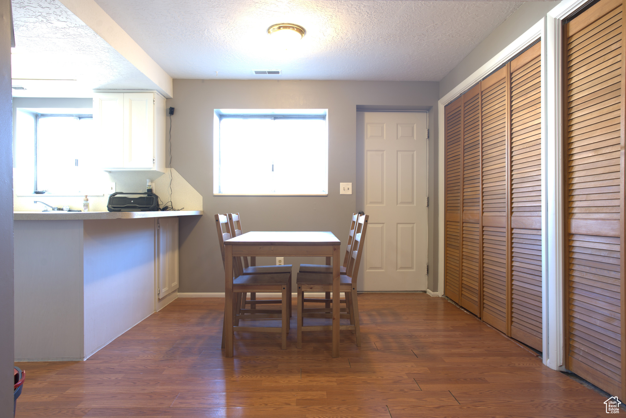 Dining area with wood finished floors, visible vents, and a textured ceiling