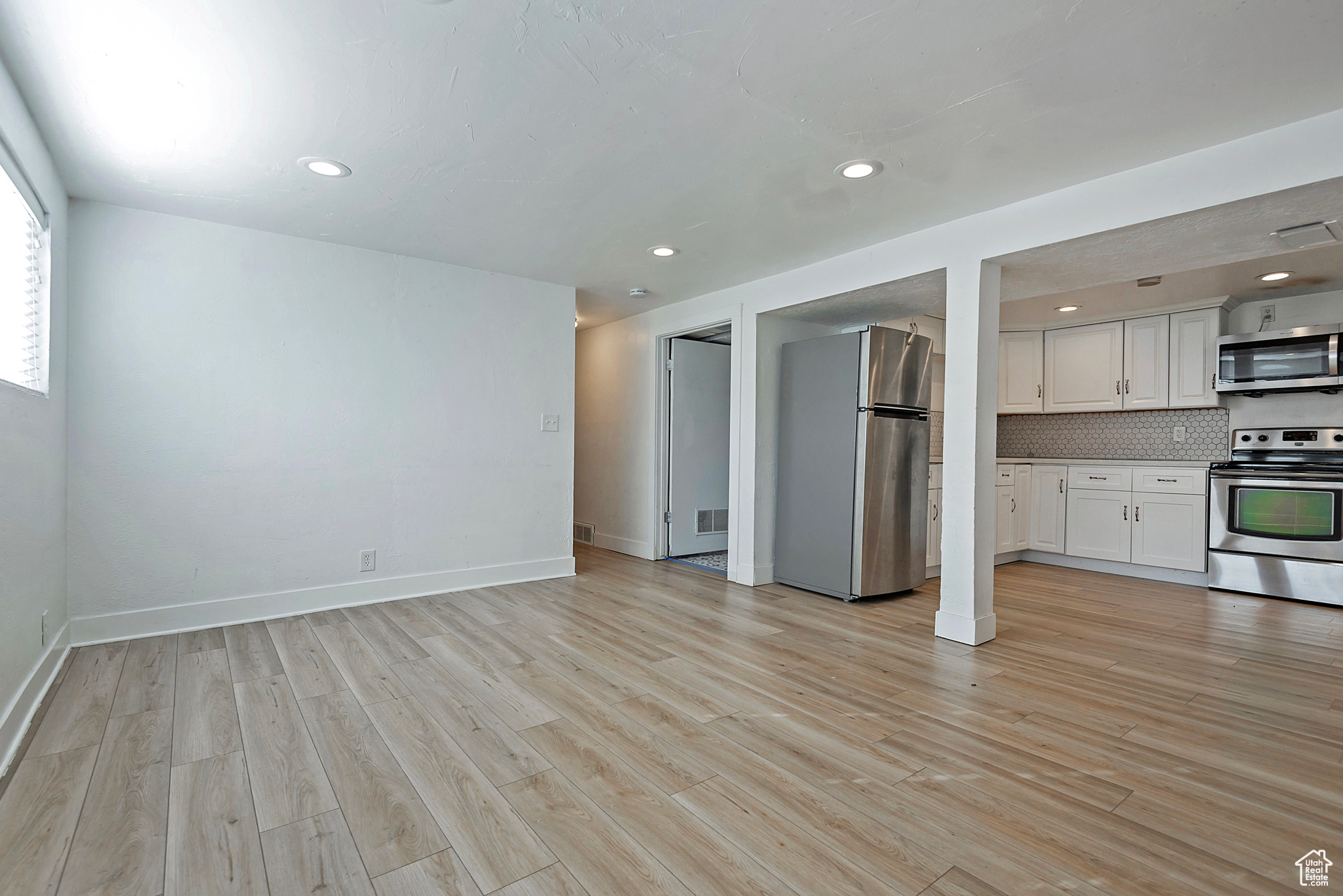 Unfurnished living room with recessed lighting, baseboards, and light wood-style floors