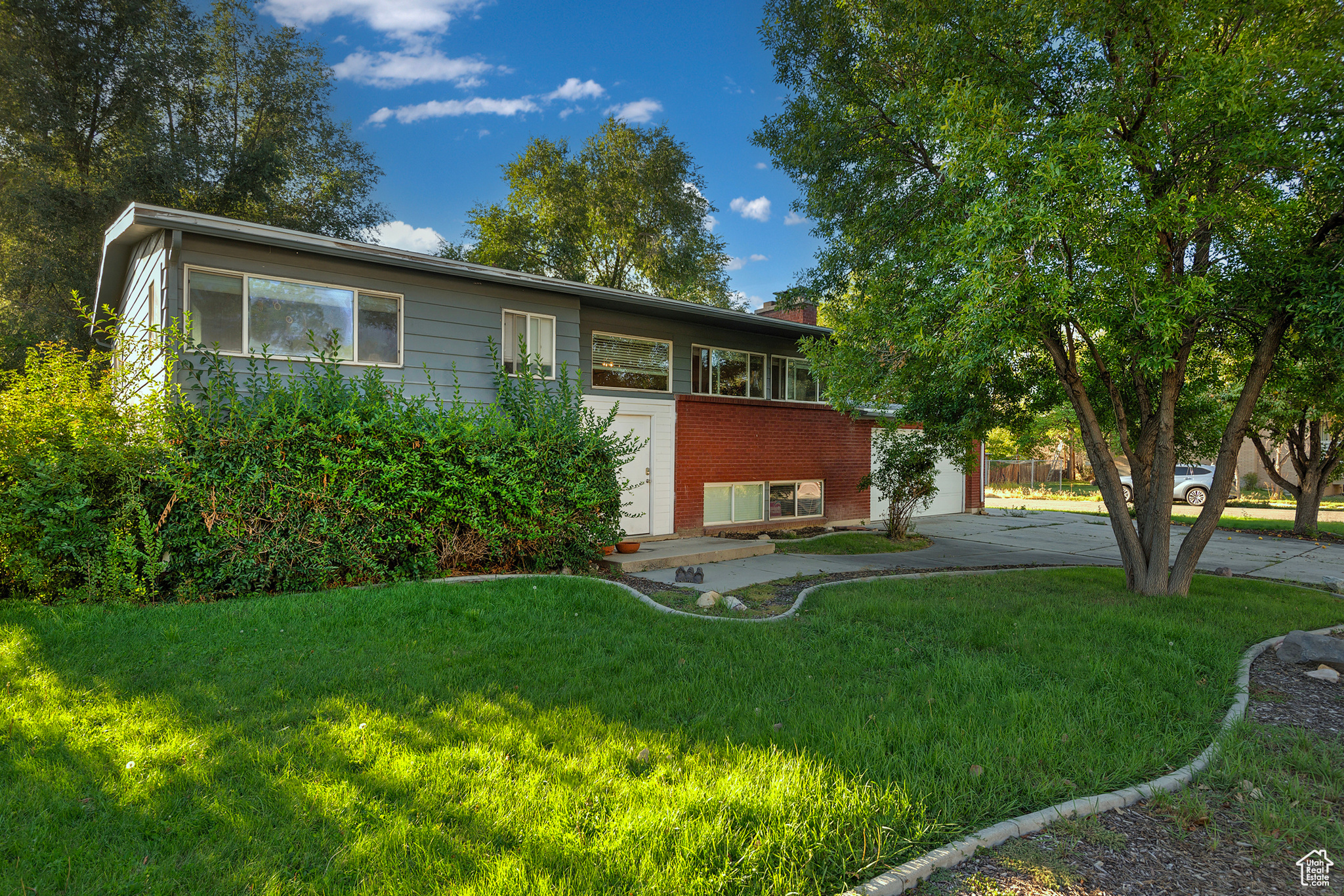 View of front of house with brick siding, driveway, and a front yard