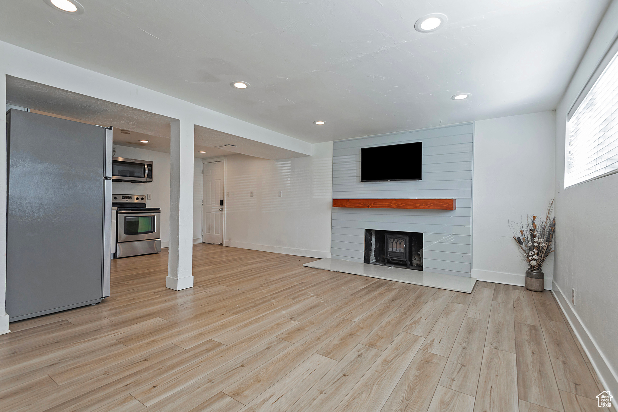 Unfurnished living room with recessed lighting, light wood-type flooring, a large fireplace, and baseboards