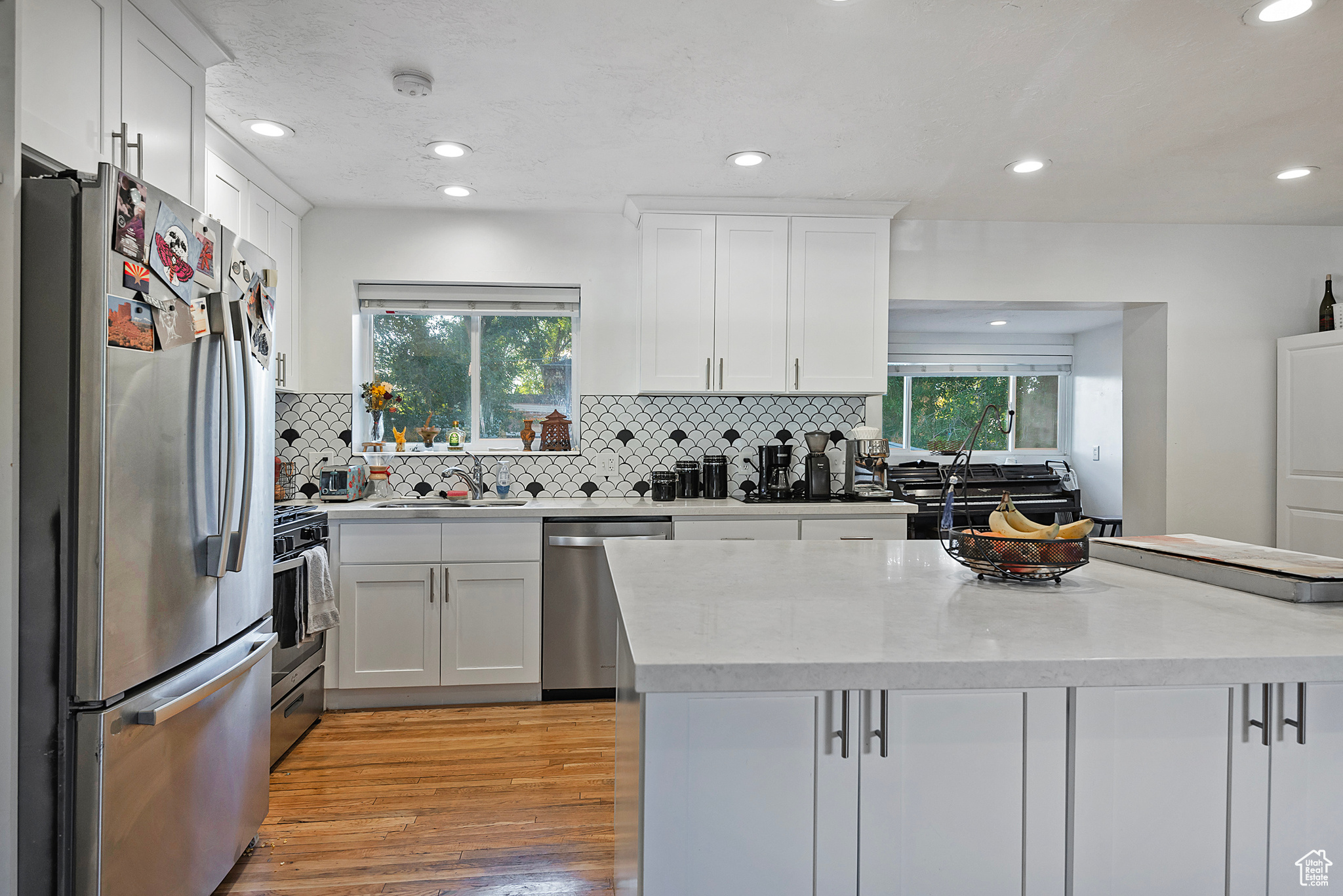 Kitchen featuring light wood-type flooring, stainless steel appliances, plenty of natural light, and white cabinetry