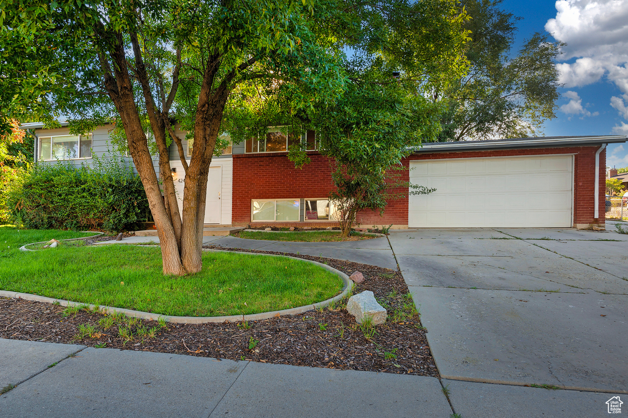 View of front facade with concrete driveway, a garage, and brick siding